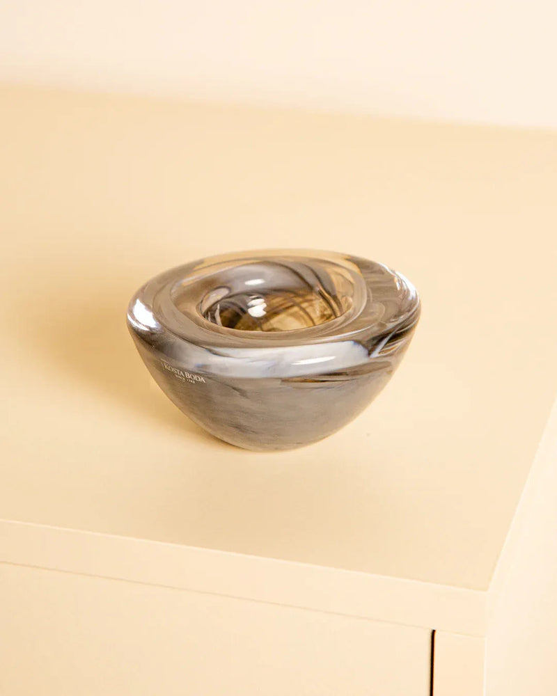 The Vide-poches "Fumé" by Kosta Boda 80's from Treaptyque is a smooth, oval-shaped blown glass piece with swirling gray and brown tones, shown on a light beige surface against a matching background.
