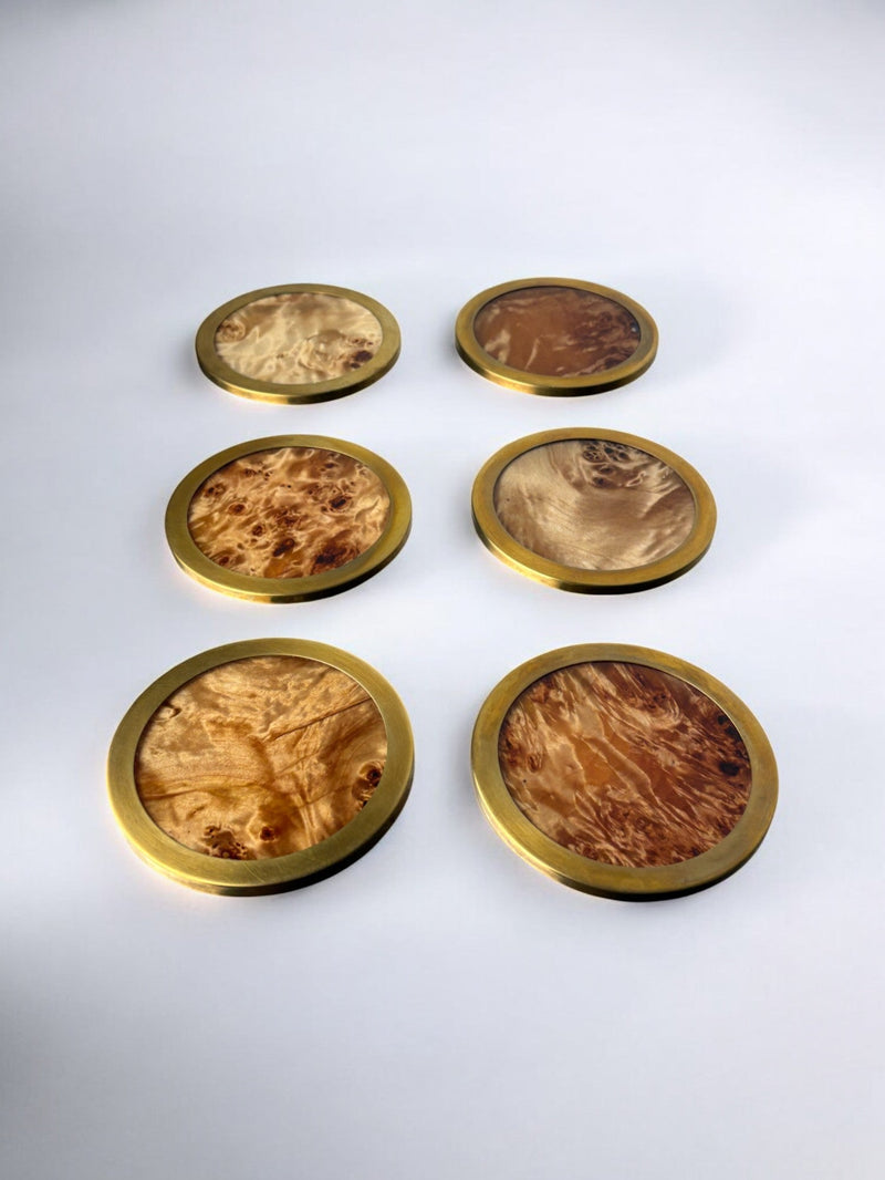 Six brass-rimmed burl wood coasters arranged in rows showing grain patterns