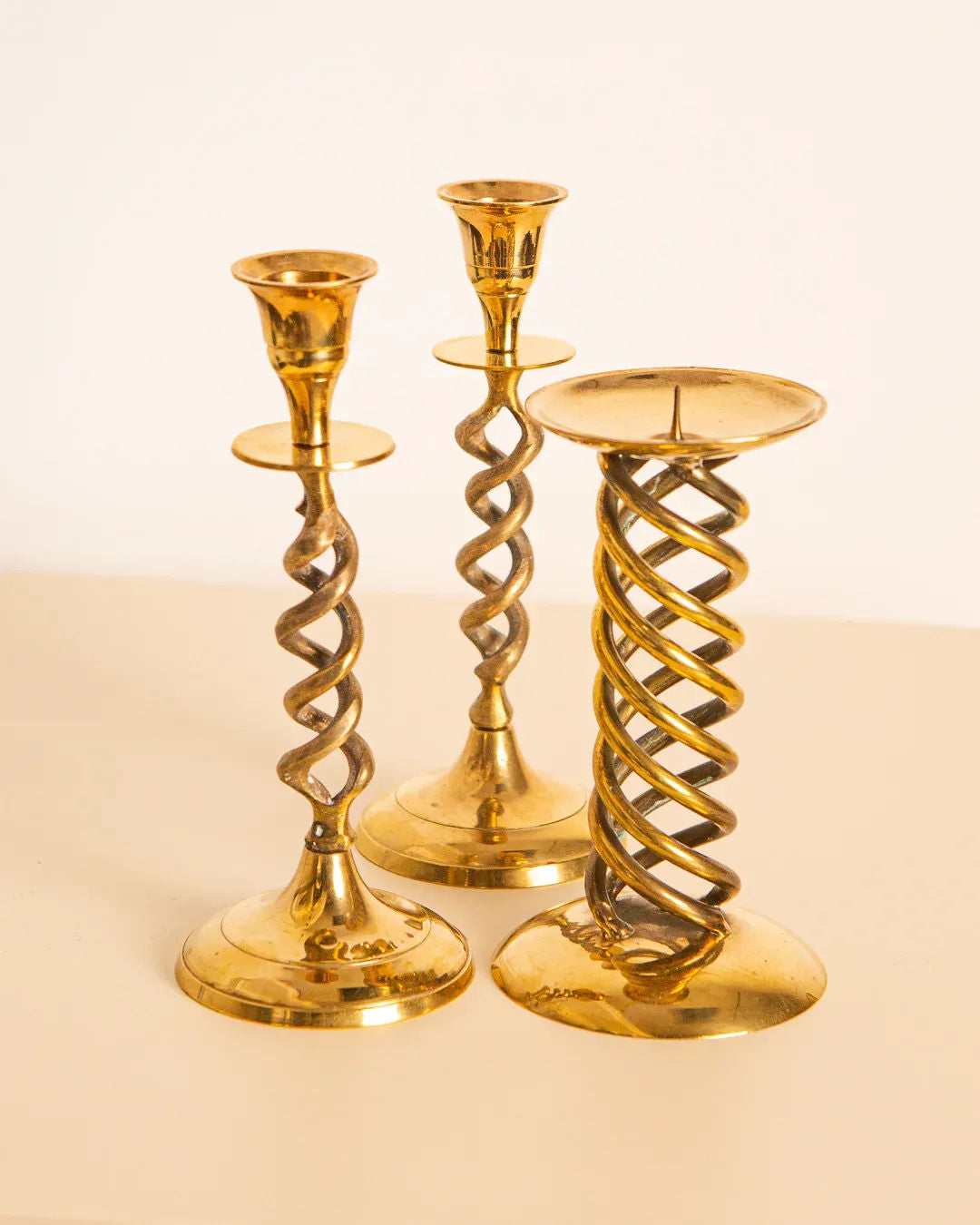 The Treaptyque set includes three Italian 60's gilded metal candleholders: two with tall spiral designs and one featuring a wider, thicker twist. These vintage pieces are displayed on a light surface against a plain background.