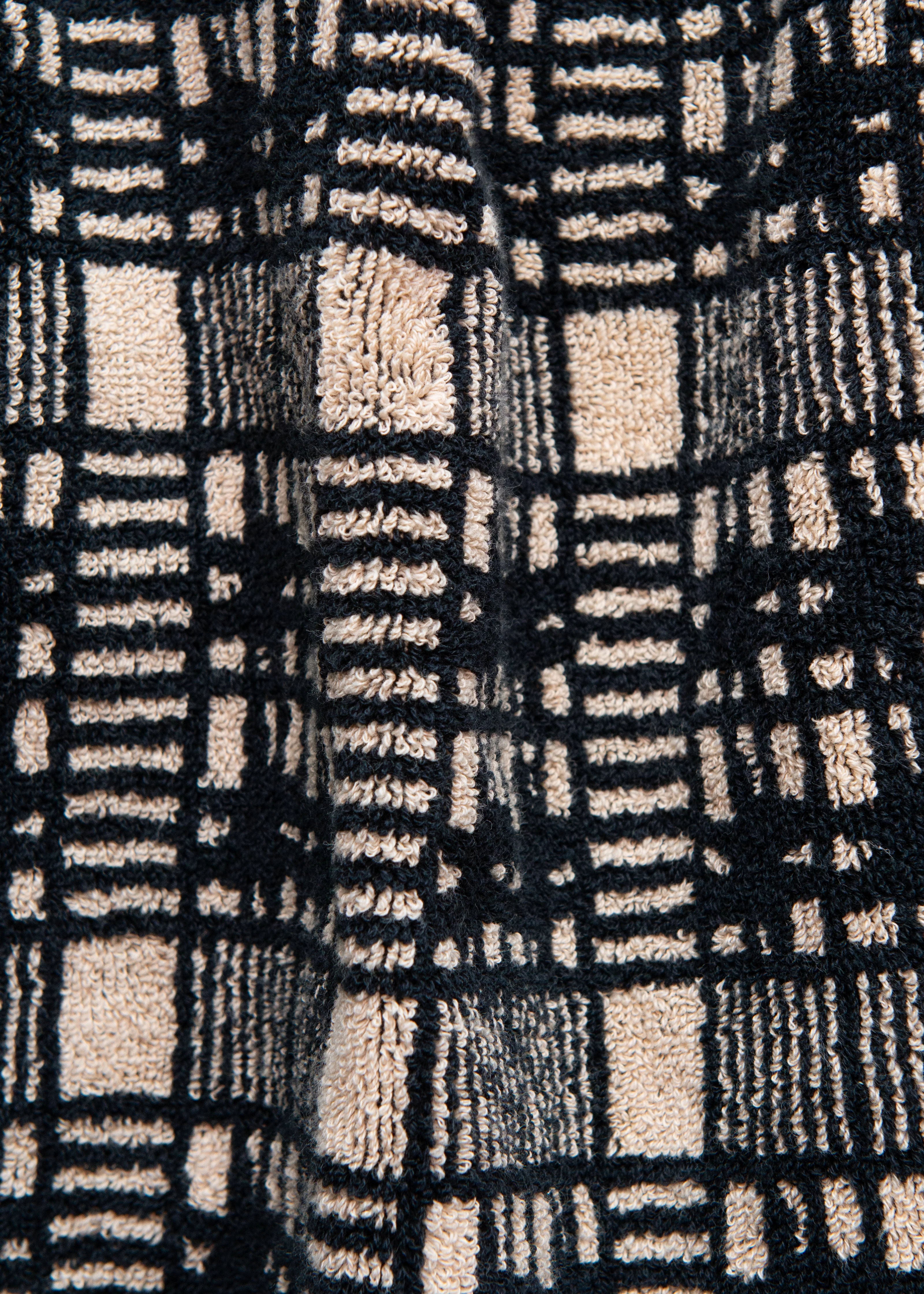 Close-up of a textured Alma Bath Towel from Autumn Sonata with a black and beige two-tone checkered design.