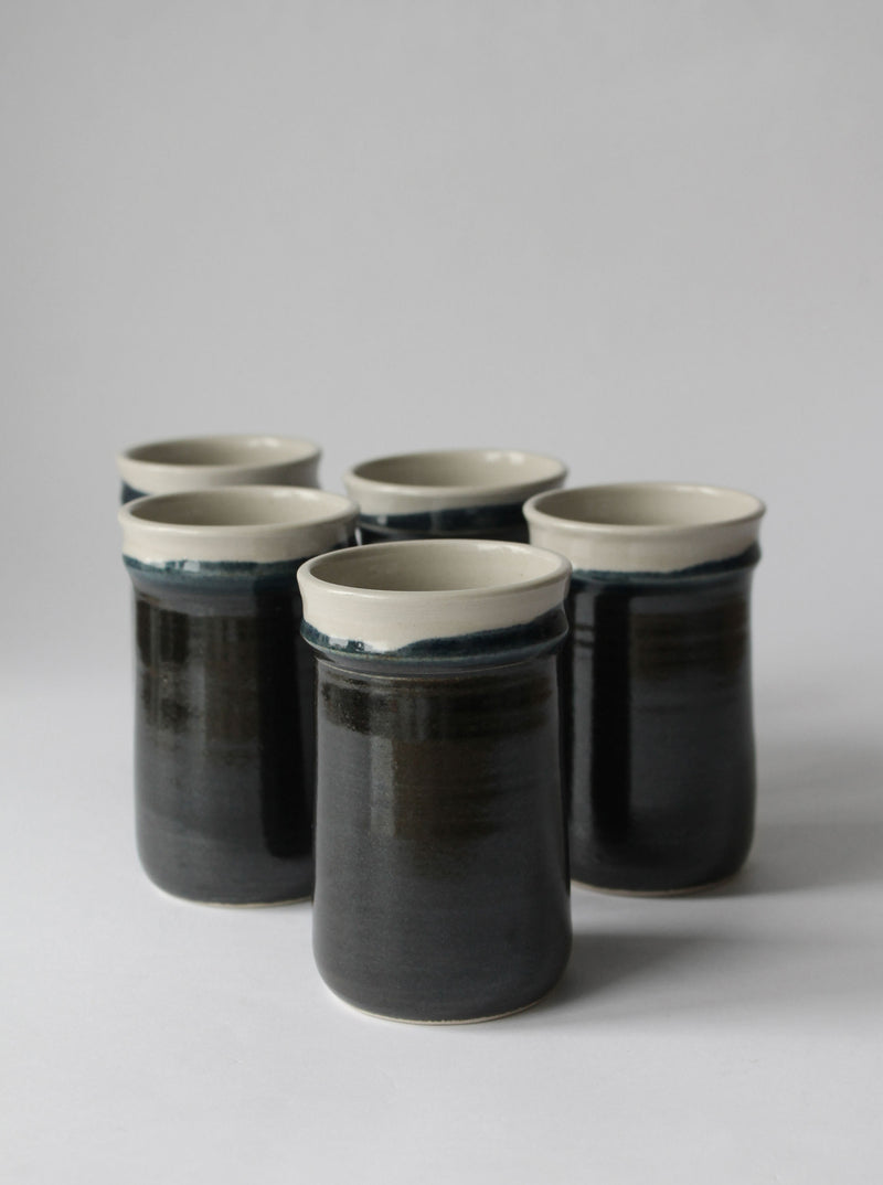 Set of five Finnish ceramic tumblers with dark glaze and cream rims