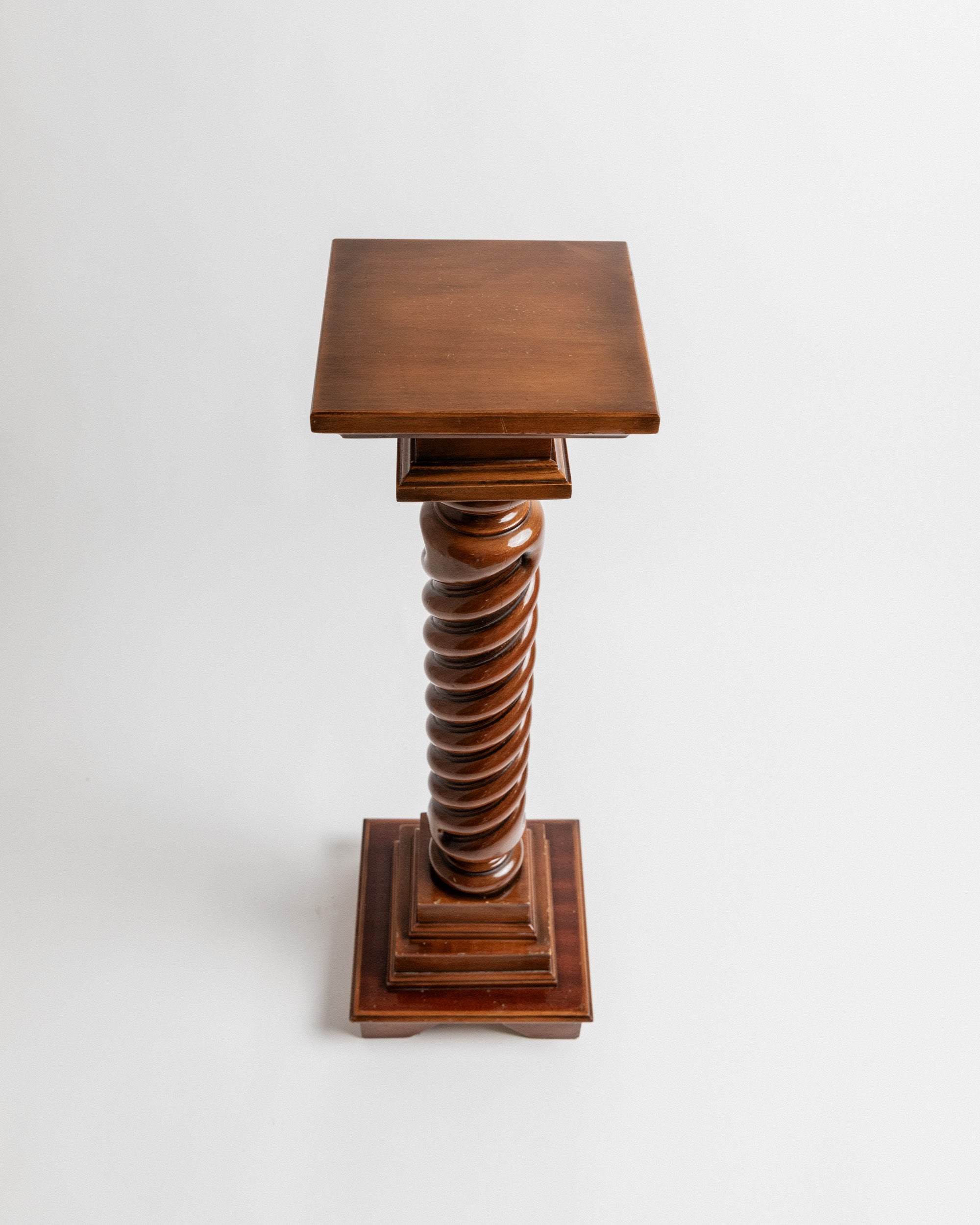 The Bottega Jacobs Wooden Stand, handcrafted in Italy in the 1960s, features a spiraled column design with a square top and base. Made of solid wood, it is enhanced by a polished dark finish.