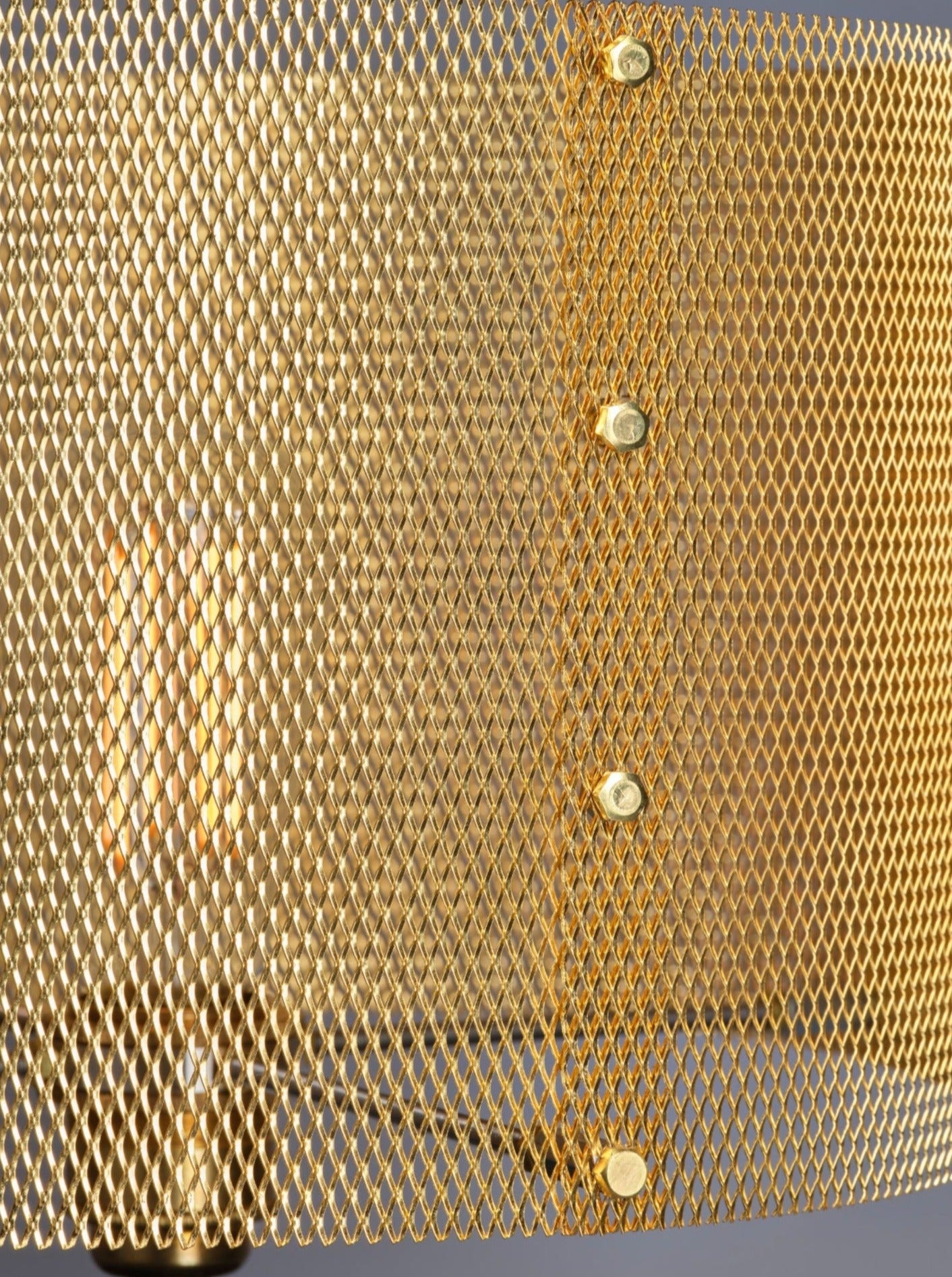 Close-up view of a Marine Breynaert Dyane Table Lamp secured with rivets, showing intricate hexagonal patterns and the shadows it casts.