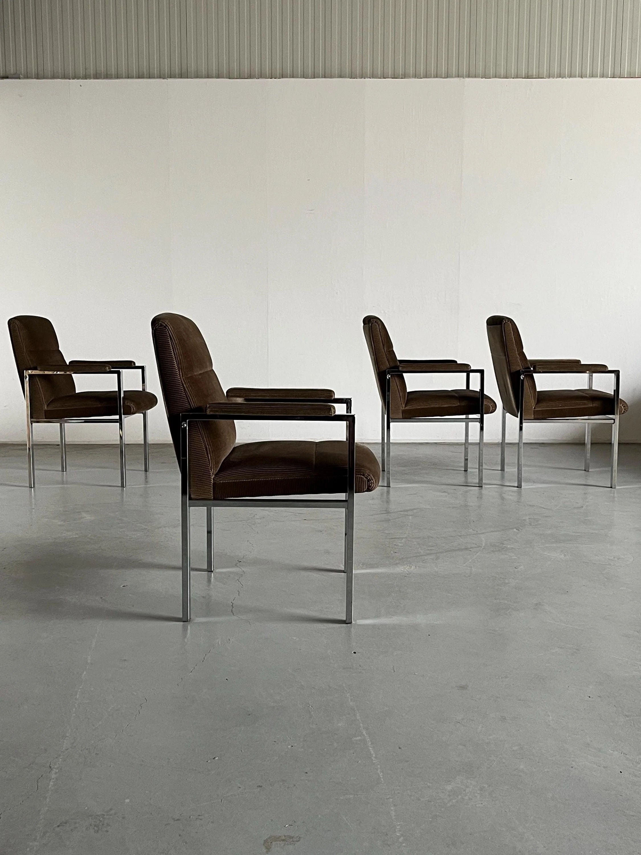 Four vintage Cherry Cargo Mid-Century Armchairs from the 1970s, featuring chrome legs and armrests, are lined up on a smooth, light gray floor against a plain white wall.