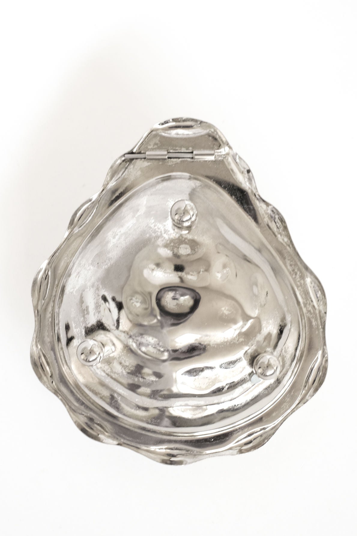 The septembre studios Shell Butter Dish is a vintage, silver dish shaped like a scallop shell with a hinged lid, shown from above on a white background. It features a wavy textured surface and visible screws.