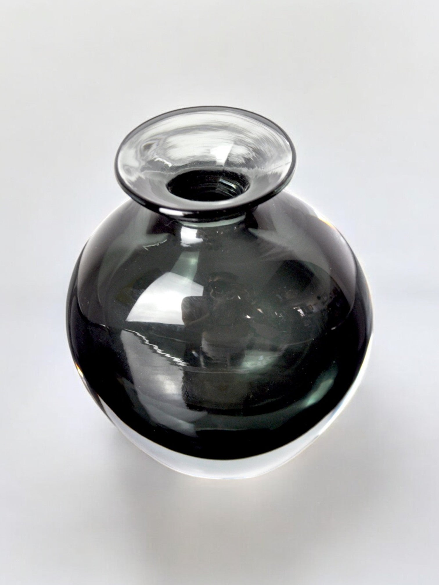 The Black vase by Vincenzo and Carlo Nason for Malamar Studio, crafted in Murano glass, Italy (1960), features a round, glossy form with a wide opening, reflecting light on its dark surface as it sits on a white background.