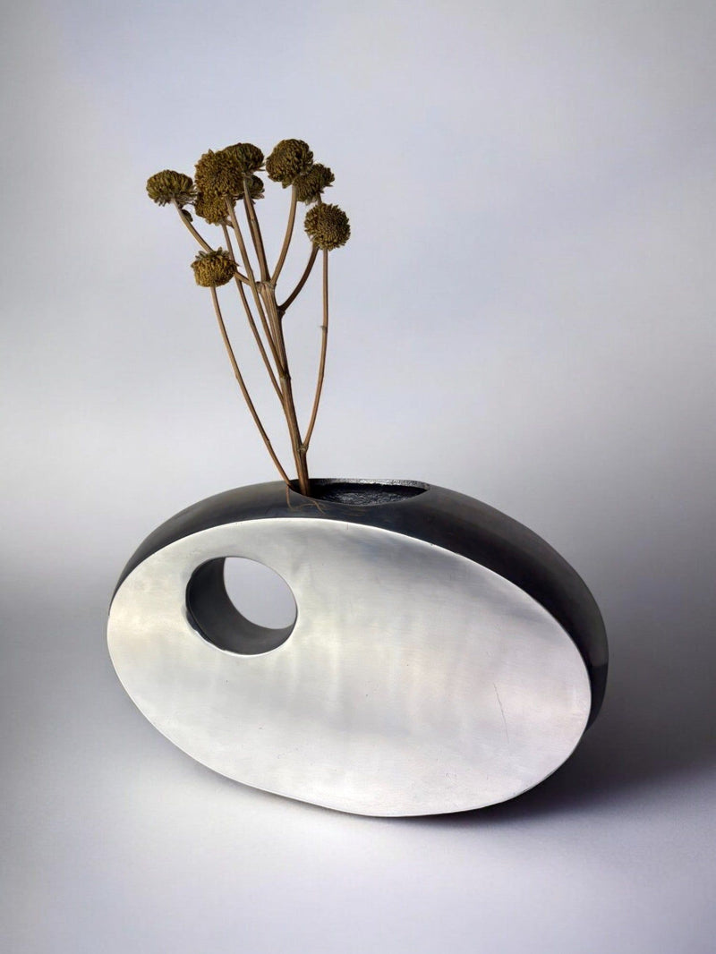 Biomorphic aluminum vase with dried stems, curved sculptural form
