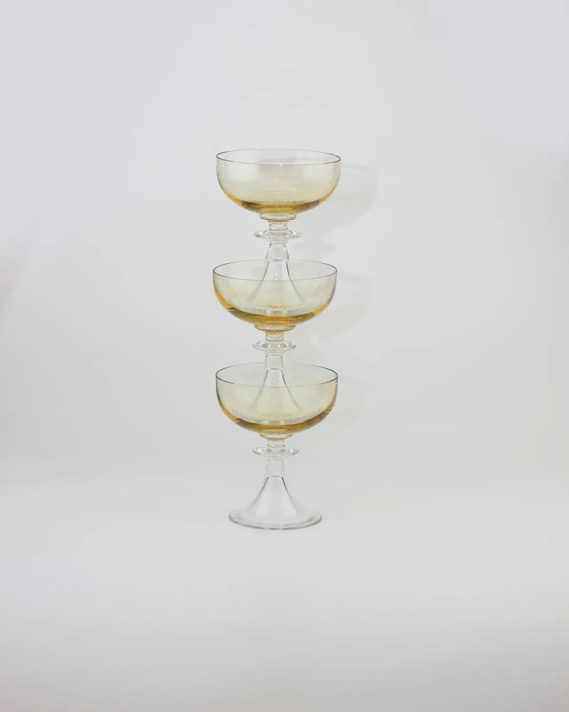 Three stacked amber crystal cocktail glasses with elegant stems