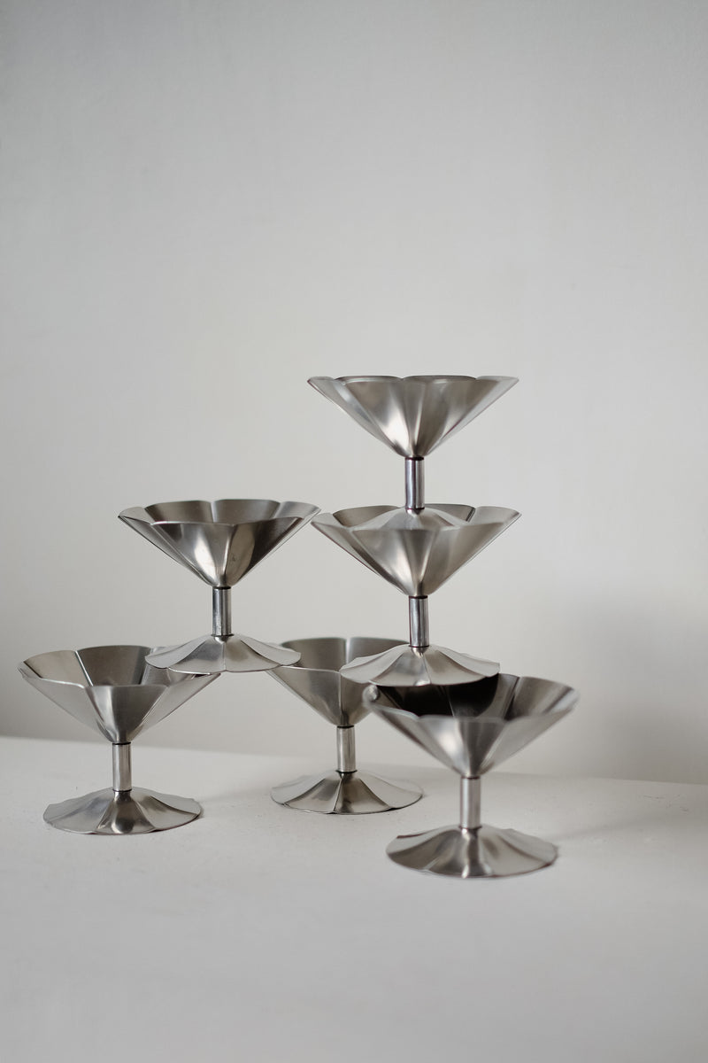 A minimalist arrangement of six septembre studios' Ice Coupes stacked in a pyramid on a white surface against a plain background.