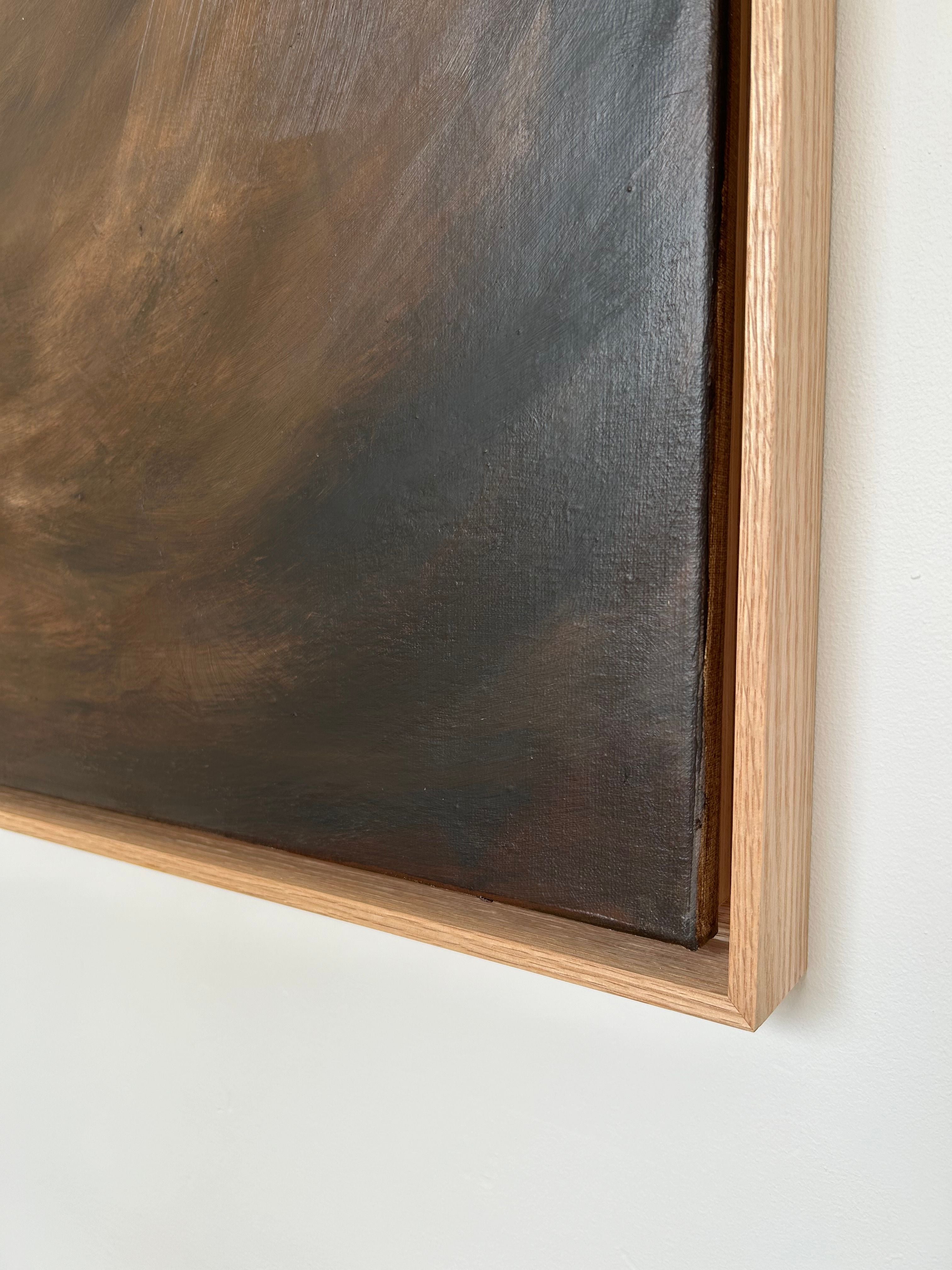 Close-up of a framed painting with an oak frame. The mixed media artwork, Shadowed Abyss - Mixed media on canvas by Mattias Storm, features abstract, dark swirls in shades of brown and black. The light-colored frame is snugly fitted around the edges, contrasting with the darker tones of the 124 x 94 cm piece.