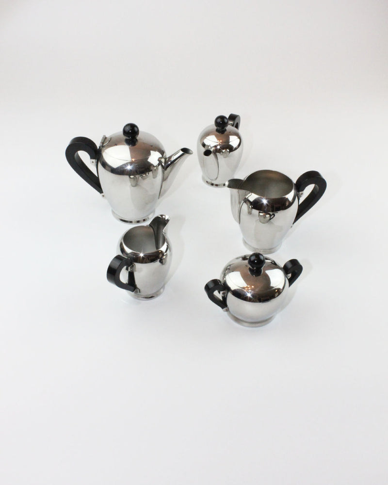 The "Bombè" Alessi Tea/Coffee Set by Boga Avante Shop, a five-piece stainless steel collection with black handles, features a teapot, coffee pot, creamer, sugar bowl with lid, and small milk jug, showcasing mid-20th-century craftsmanship on a white background.