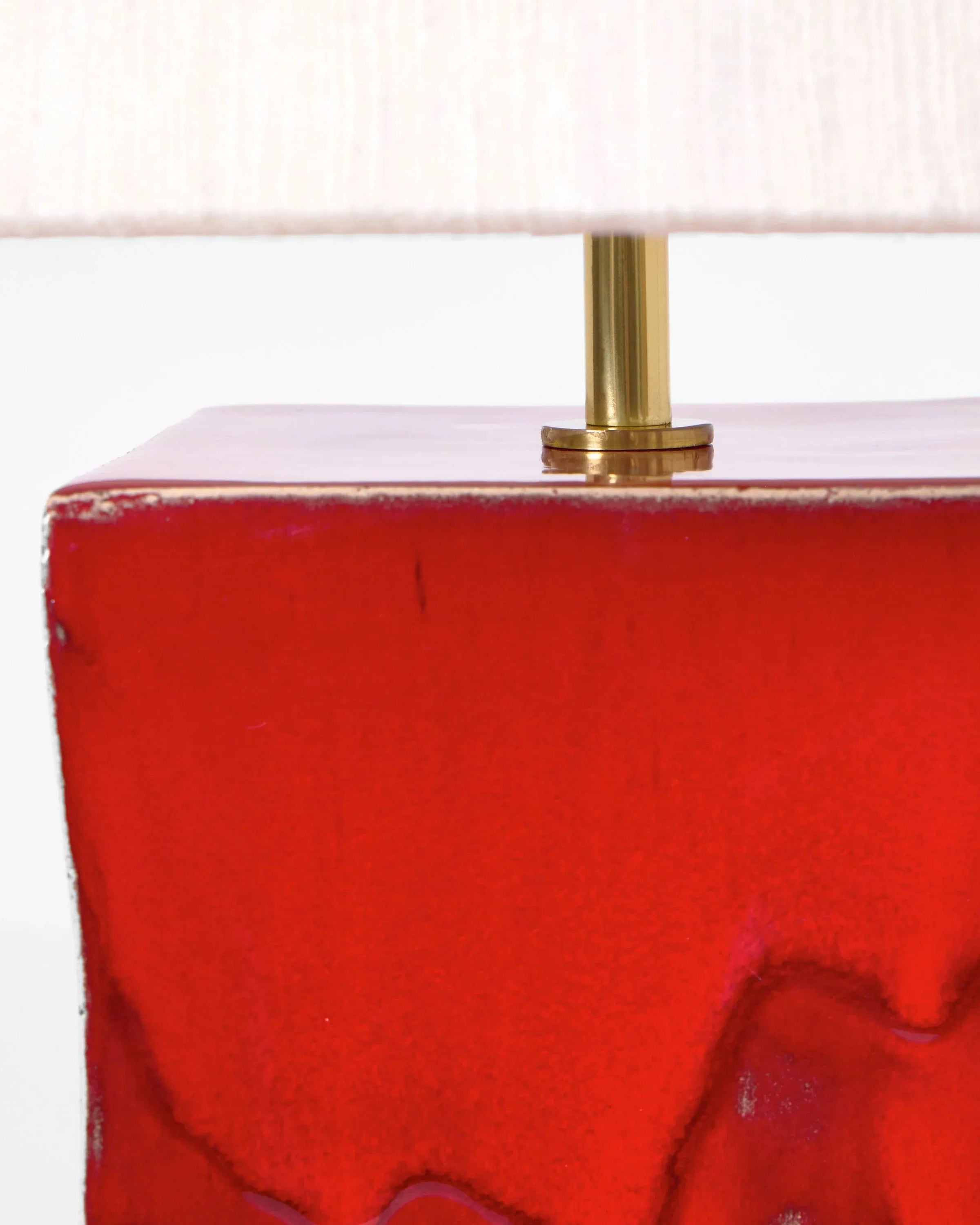 Close-up of Project 213A's Arouca Table Light Red, showcasing its glossy red ceramic base with subtle texture, brass stem, and partially visible white lampshade—a unique, handcrafted lighting piece.