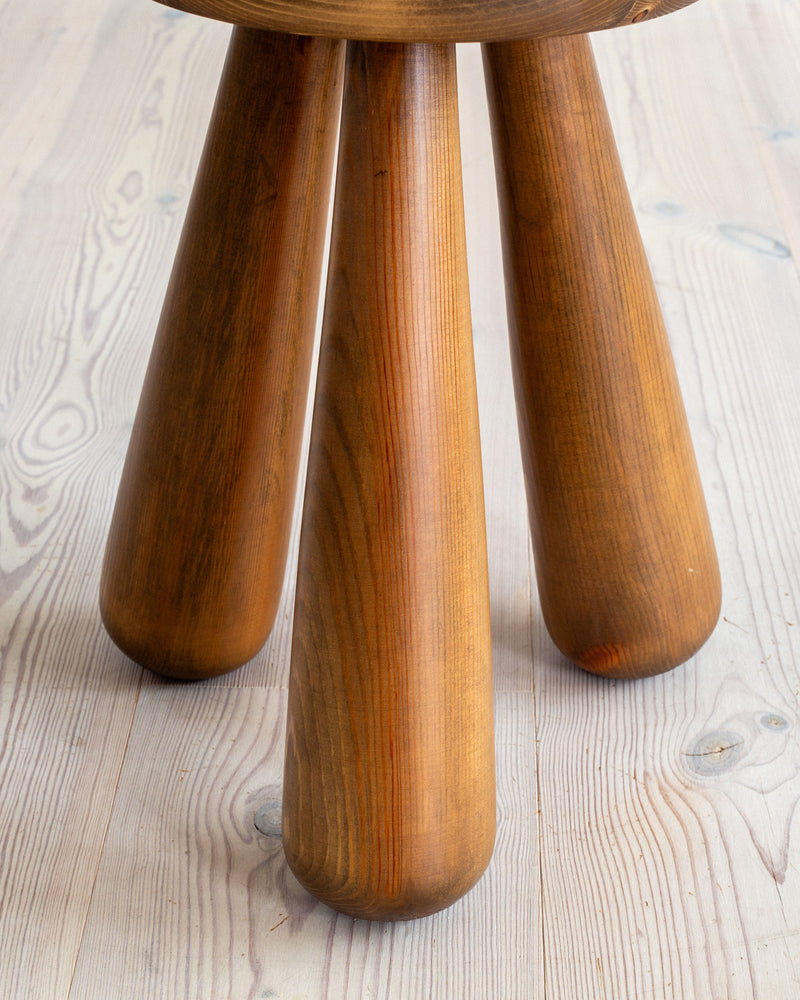 Close-up view of vintage pine stool's tapered wooden legs
