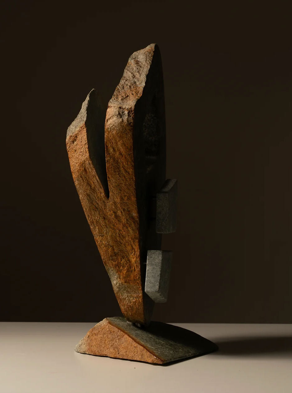 Les Objets Amsterdam's Two-toned Abstract Sculpture features a modernist design crafted from natural brown stone with jagged edges. It stands upright on a flat base with asymmetrically arranged gray blocks, set against a dark backdrop.