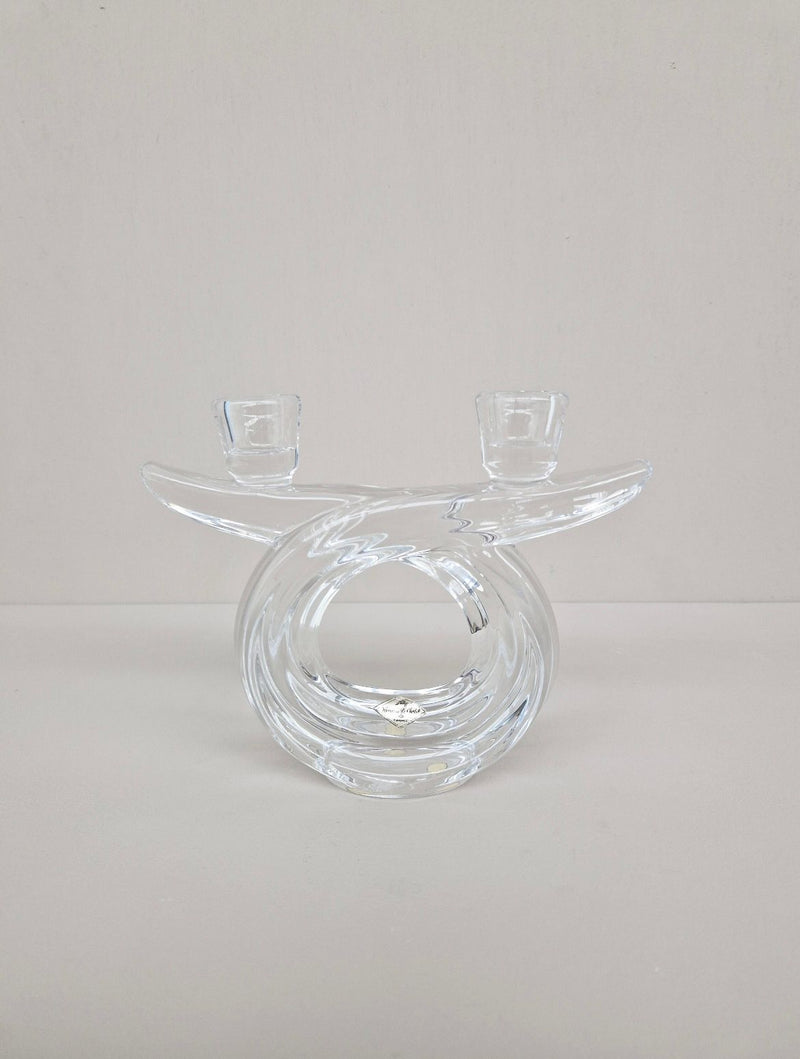 The Crystal Candle Holder 1960s by Flock Studio features a clear glass design with a sculptural, twisted circular shape, reflecting mid-century elegance with dual top candle slots, set against a plain light background.