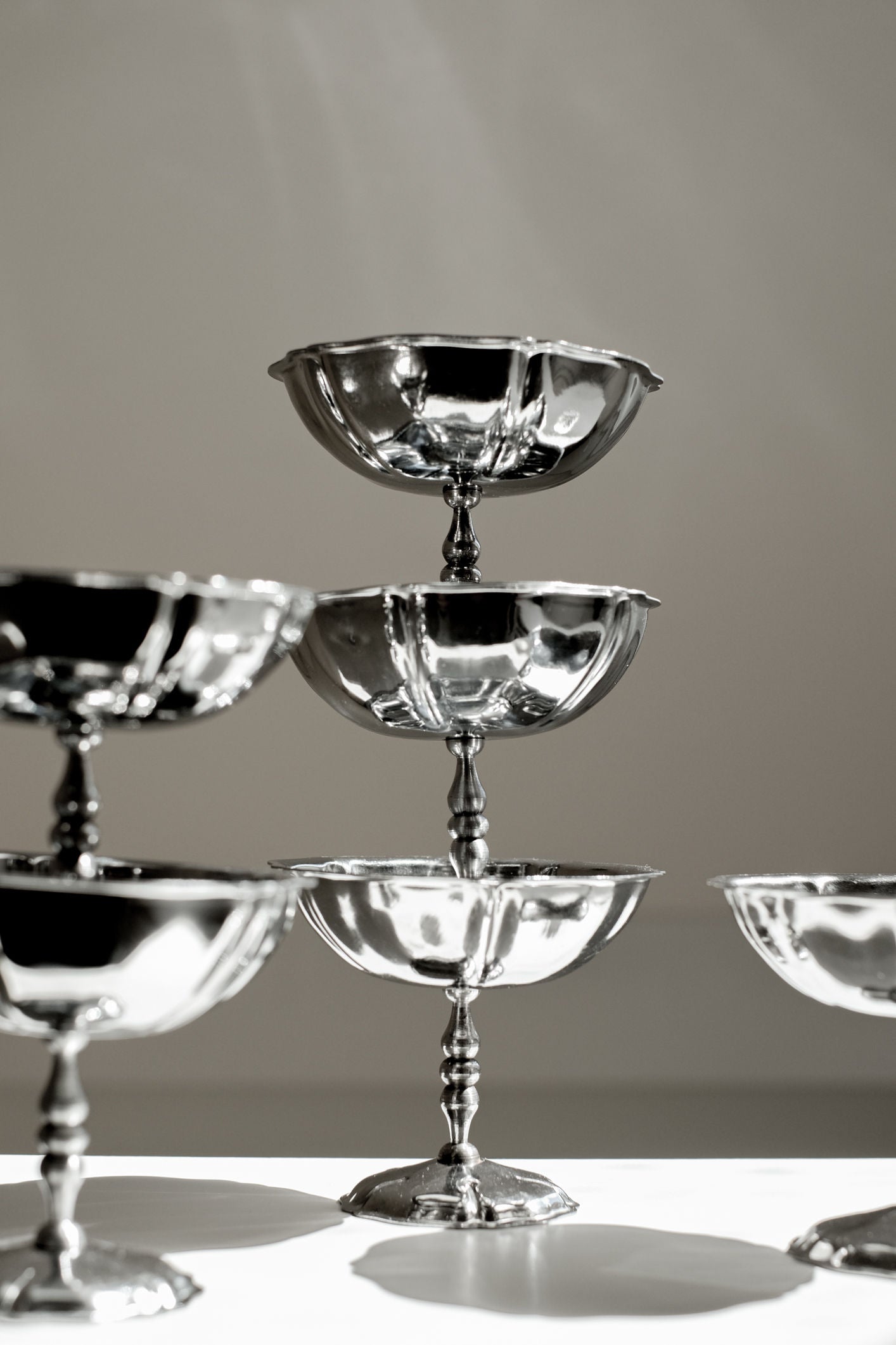 A close-up of the septembre studios Set of Six Ice Coupes, sleek stainless steel glasses artfully stacked with one atop the rest, reflecting light on a simple background for a vintage-inspired touch.