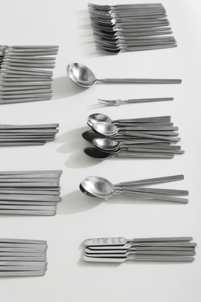 Stainless steel Obelisk flatware pieces arranged in organized stacks