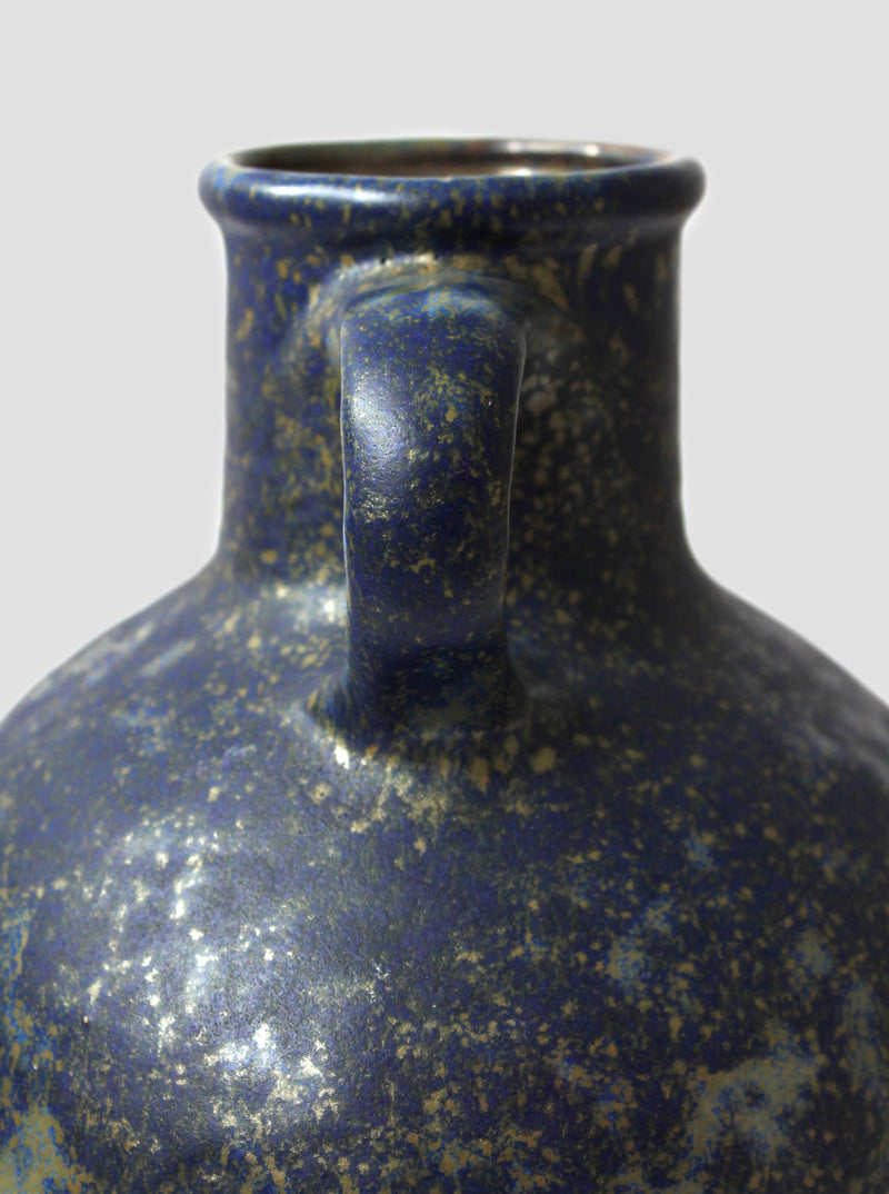 Close-up detail of vintage ceramic jug's speckled blue glaze and handle
