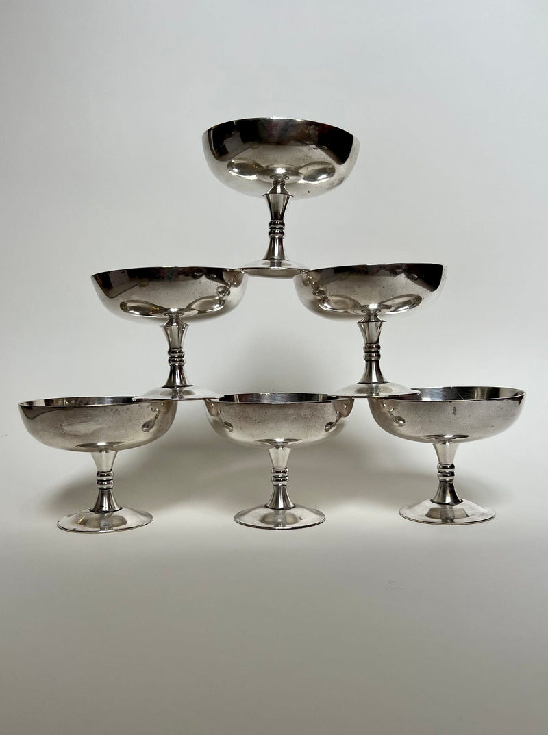Six elegant silver champagne coupes stacked in pyramid formation