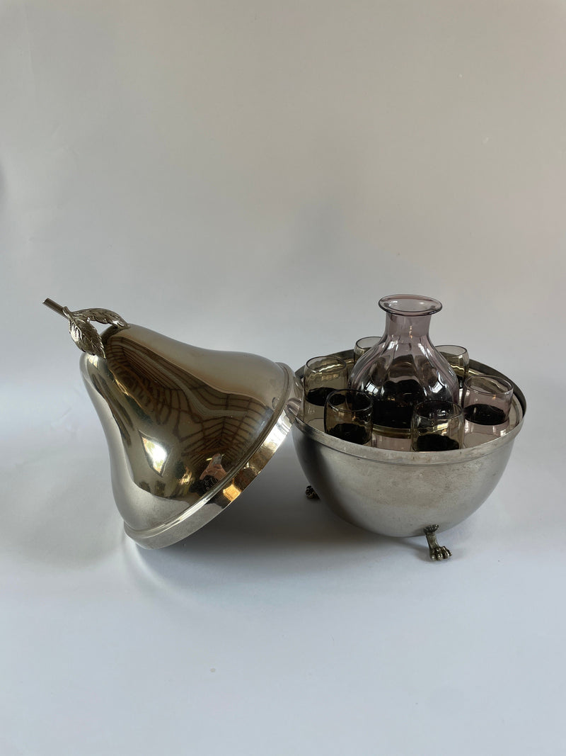 The Mid-century French Pear Carafe and Glasses by Maud Vaughan features a chrome-plated pear-shaped container with a removable lid, revealing a glass jar inside, surrounded by small compartments. The elegant piece rests gracefully on decorative feet against a neutral background.