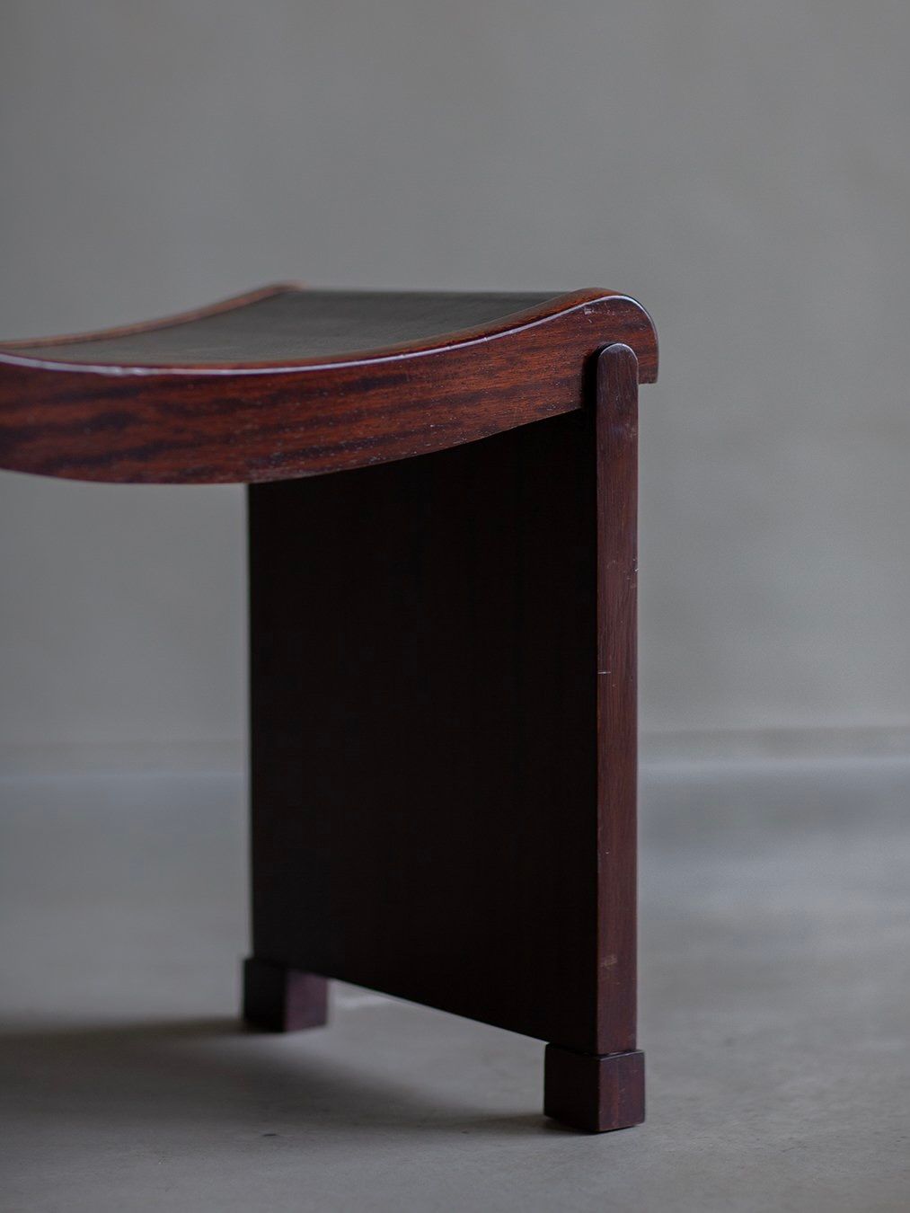 Against a plain background stands the Bicci de' Medici Pierre Chareau - Curule Model No. MT 1015 Stool, a wooden chair showcasing its dark wood grain and simple Art Deco design reminiscent of Pierre Chareau as it rests on a flat surface.