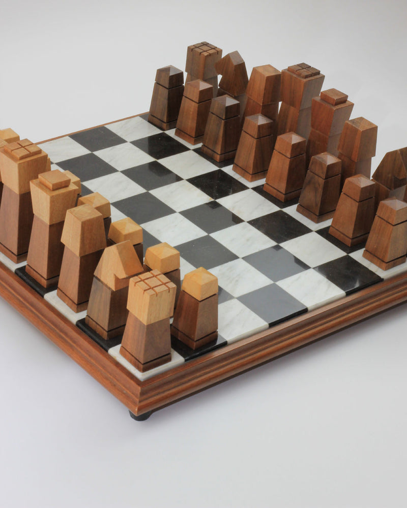 Introducing the Wooden and Marble Chessboard by Boga Avante Shop, a modern set featuring a wooden board paired with unique, minimalist hand-carved pieces. These geometric pieces showcase straight lines and angles in light and dark wood tones, all perfectly arranged on a checkered surface ready for the start of an exciting game.