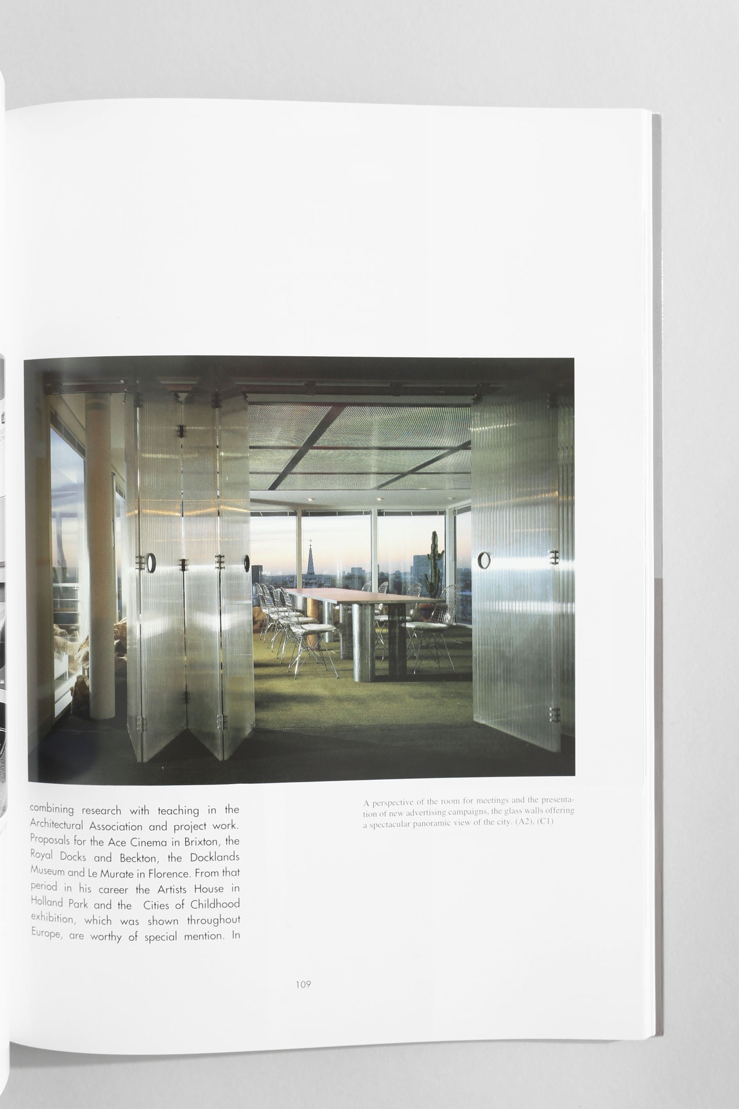 A photograph from Villa's 'Commercial Space: Offices, Design and Layout' book highlights a modern conference room with glass walls, a long table, and chairs bathed in natural light from expansive windows.