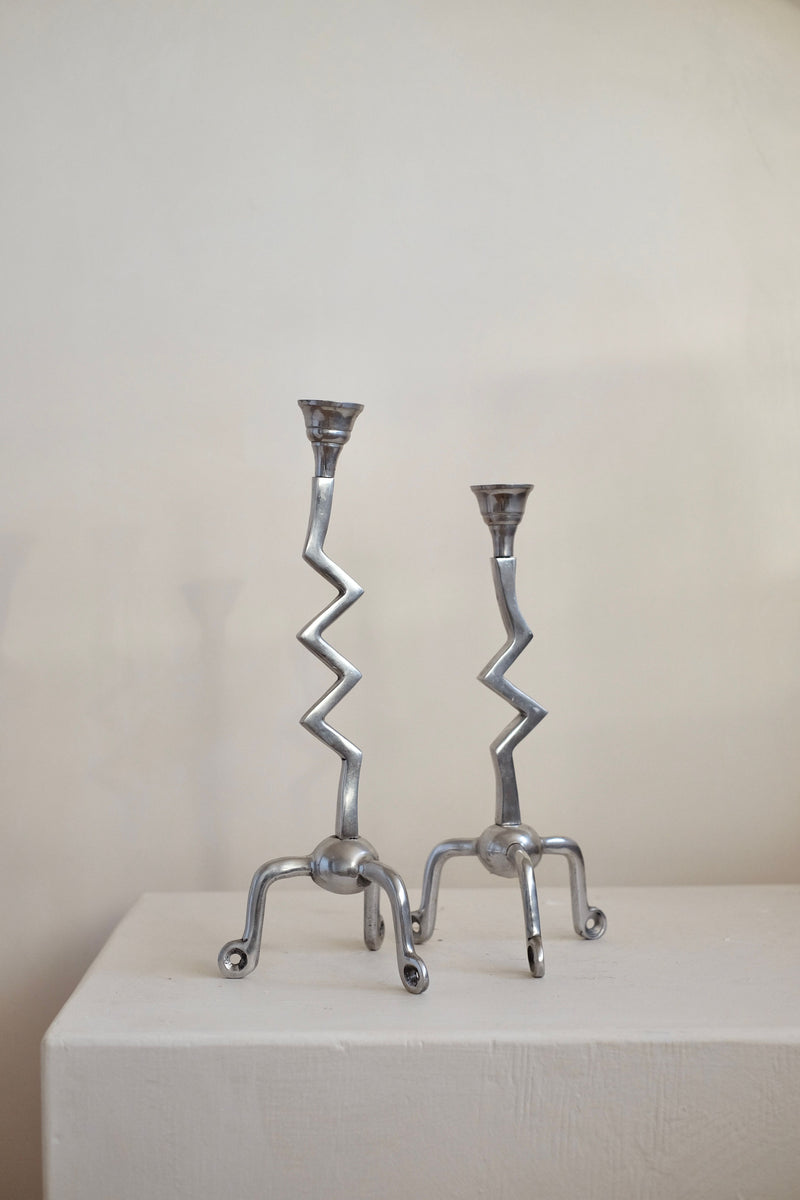 A pair from the Set of Zigzag Candleholders by septembre studios is displayed on a white surface against a simple, light backdrop. Their rare design features zigzag stems and claw-like bases, offering an abstract and artistic look reminiscent of vintage zilver craftsmanship.