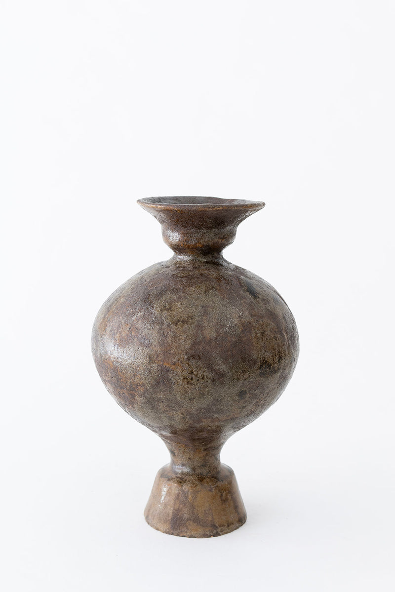 The Lekytho Bufalo Vase by Canoa Lab is a rustic, handmade stoneware piece with earthy brown and gray tones, round body, wide flared rim, and a narrow flared base, displayed against a plain white background.