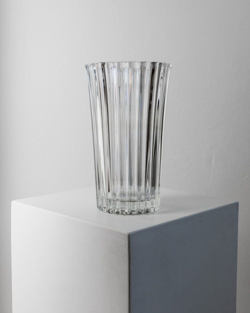 Clear glass ribbed vase displayed on geometric white pedestal