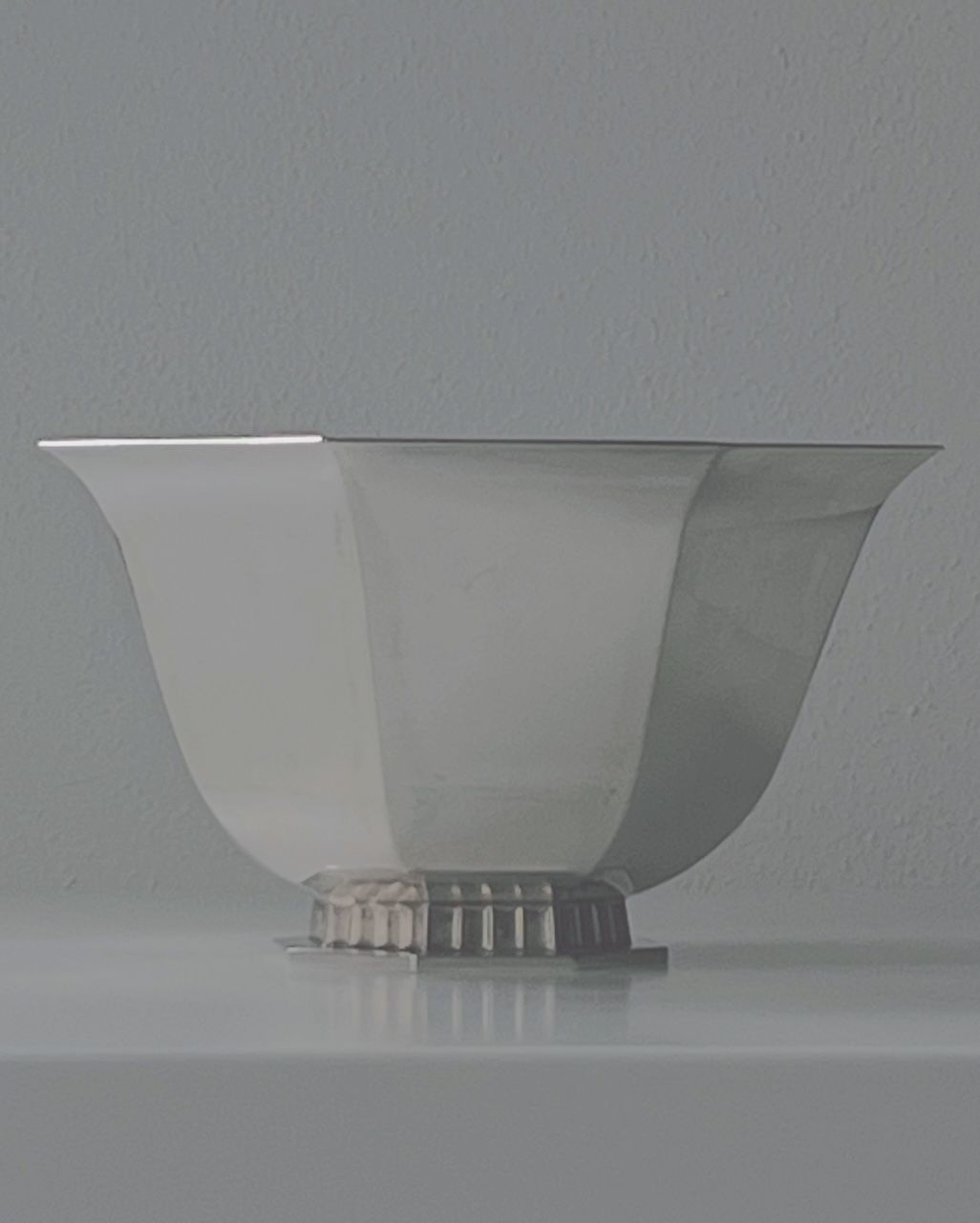 The Art Deco Silver Bowl 1949 by Médecine features a sleek, angular design with a wide rim and narrow base against a muted background. Its polished silver surface subtly reflects light, embodying modernist sophistication reminiscent of art deco elegance.