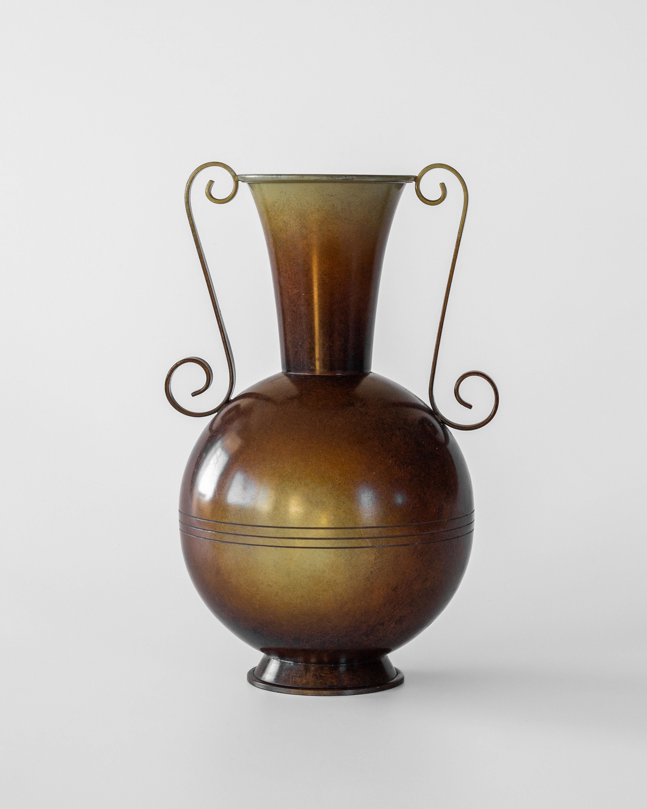 The Spigel Swedish Art Deco Bronze Vase features a round body, narrow neck, and two ornate spiraling handles. Its polished surface on a white background reflects 1930s Scandinavian vintage charm.