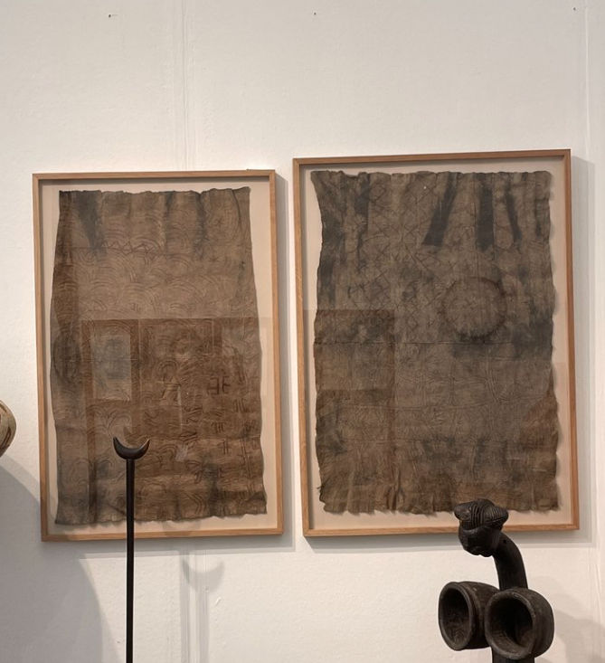 Two framed Ituri bark cloth paintings displayed on white gallery wall