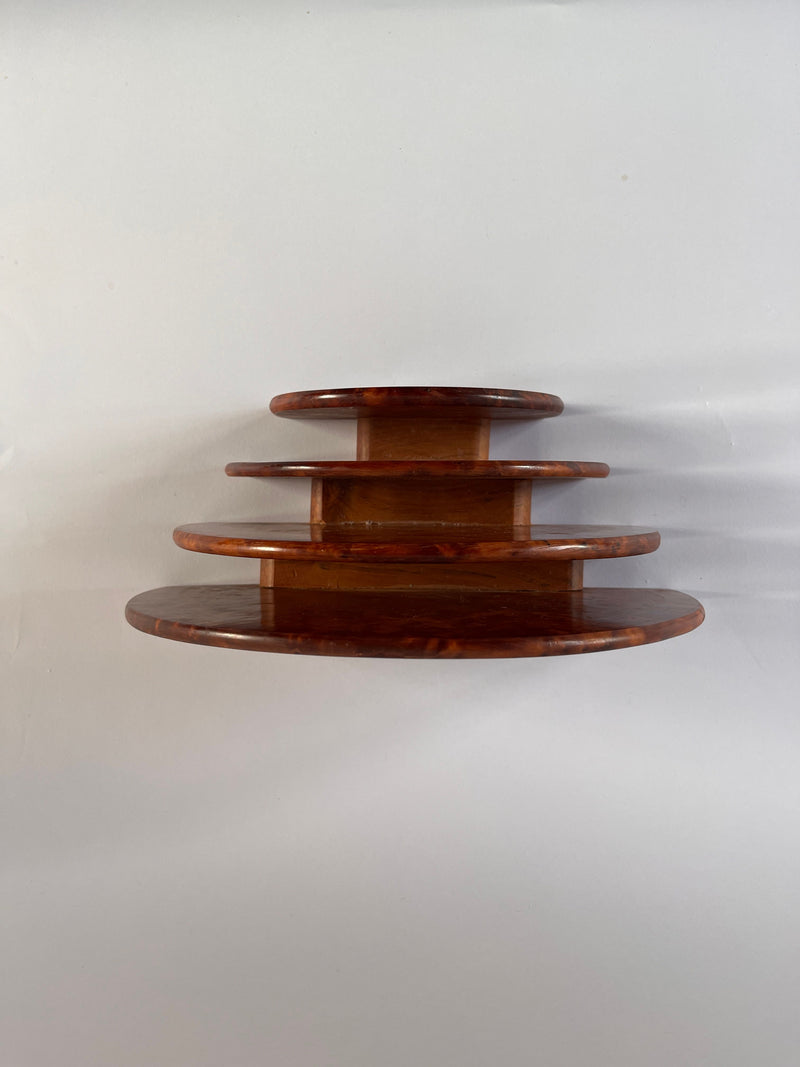 A stack of four round shelves made from Burr walnut veneer, designed by Maud Vaughan and elegantly crafted in decreasing sizes from bottom to top against a plain, white background—perfect as a stylish desk organiser.