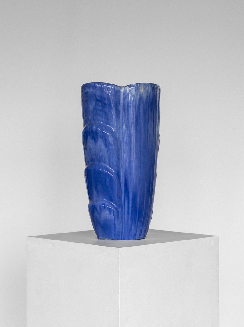 A Large Vase by Gunnar Nylund from the 1960s, crafted under the Spigel brand, stands on a plain white pedestal against a neutral gray background. The blue ceramic vase boasts an abstract, textured pattern and features a wavy, irregular shape that adds a unique artistic touch reminiscent of Scandinavian Mid-Century Studio Pottery.