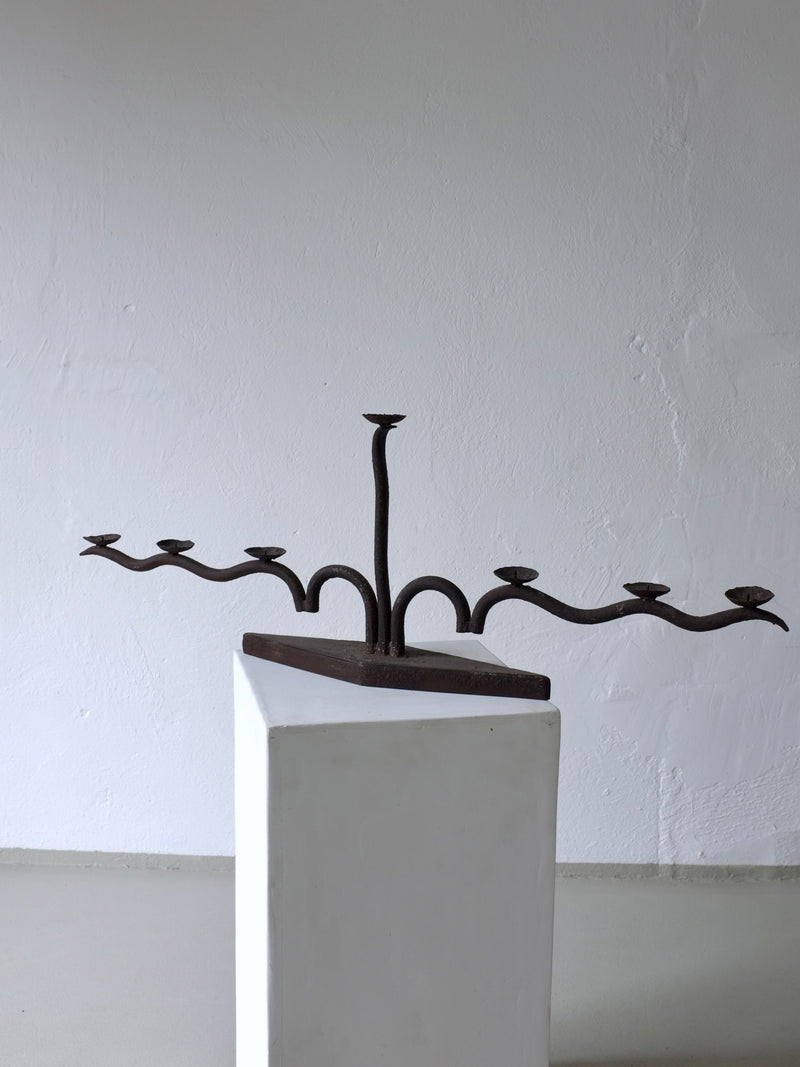 Large brutalist wrought iron candelabra displayed on white pedestal