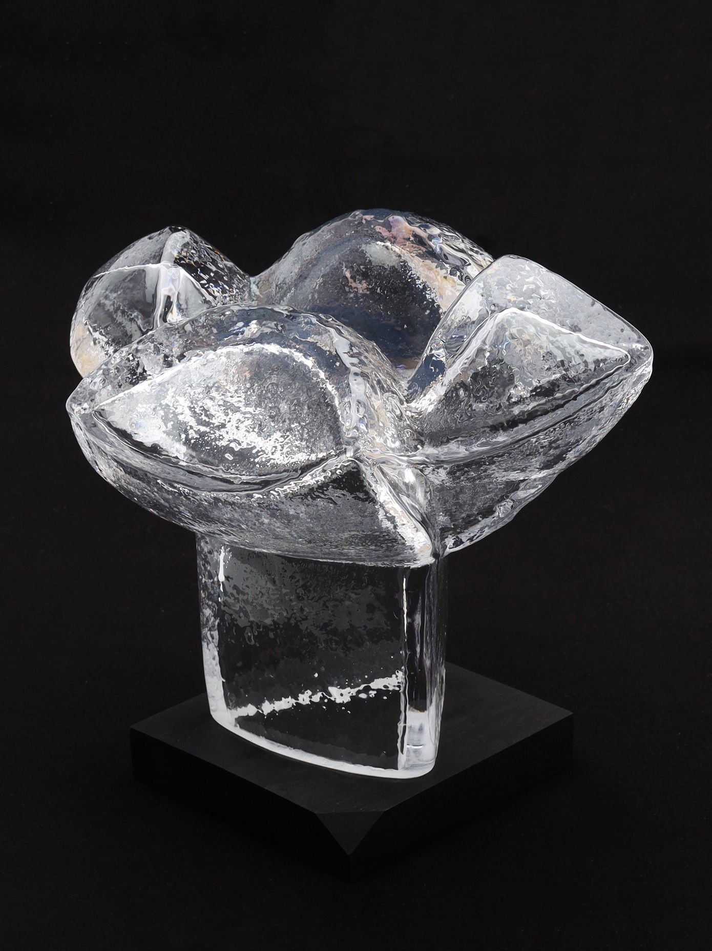 The Very Large Abstract Glass Sculpture by RELIC LONDON is showcased against a black background. This exquisite piece resembles a blooming flower or organic form, crafted by a renowned Swedish artist. It boasts smooth, translucent surfaces and intricate textures, making it ideal for any art collector. The sculpture features stunning light reflections and includes a sturdy base for secure display.