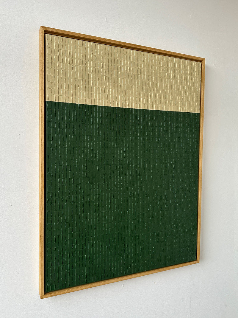 Introducing "Buff Verte" by Roi Elmaliah, a framed abstract painting in oil on canvas. This piece features a textured two-tone design with a beige upper section and a dark green lower section. The texture is reminiscent of Amsterdam's charming architecture, resembling a grid of small, raised rectangles.