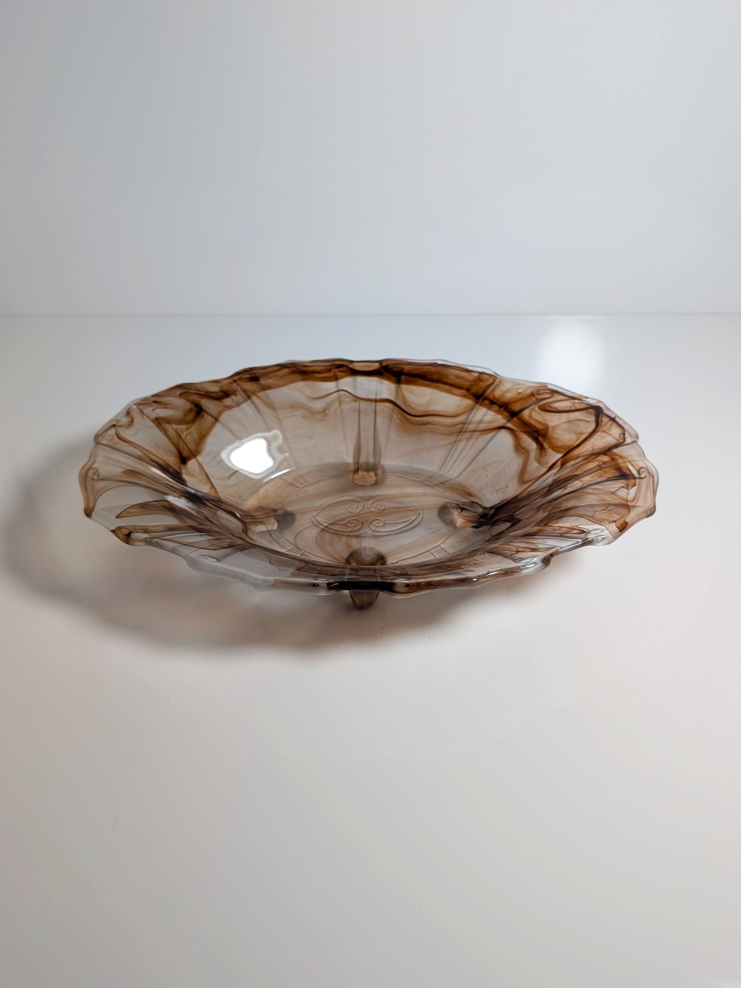 The German Art Deco Cloud Glass Bowl circa 1930 by Dodo Vintage features a translucent, wavy-edged design with a brown and amber swirl. Reminiscent of Walther Glas, it rests on a white surface reflecting light across its glossy finish.