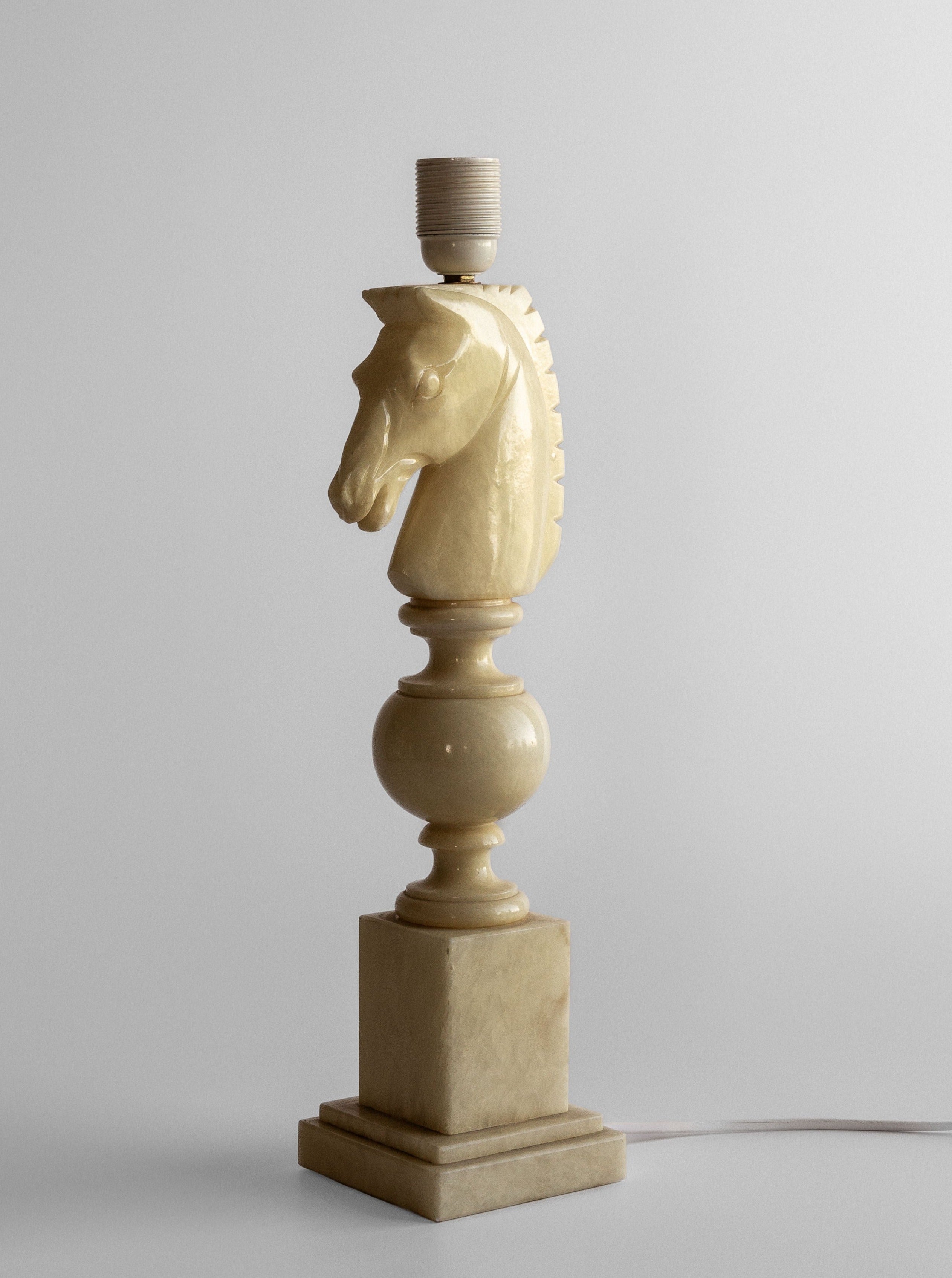 The Spigel "White Knight Alabaster Table Lamp" from the 1970s features a vintage Italian design with an intricately carved horse head as the base. Made of light beige alabaster, it showcases detailed features on the horse's mane and face. With a rectangular base, this unlit lamp exudes classic charm.