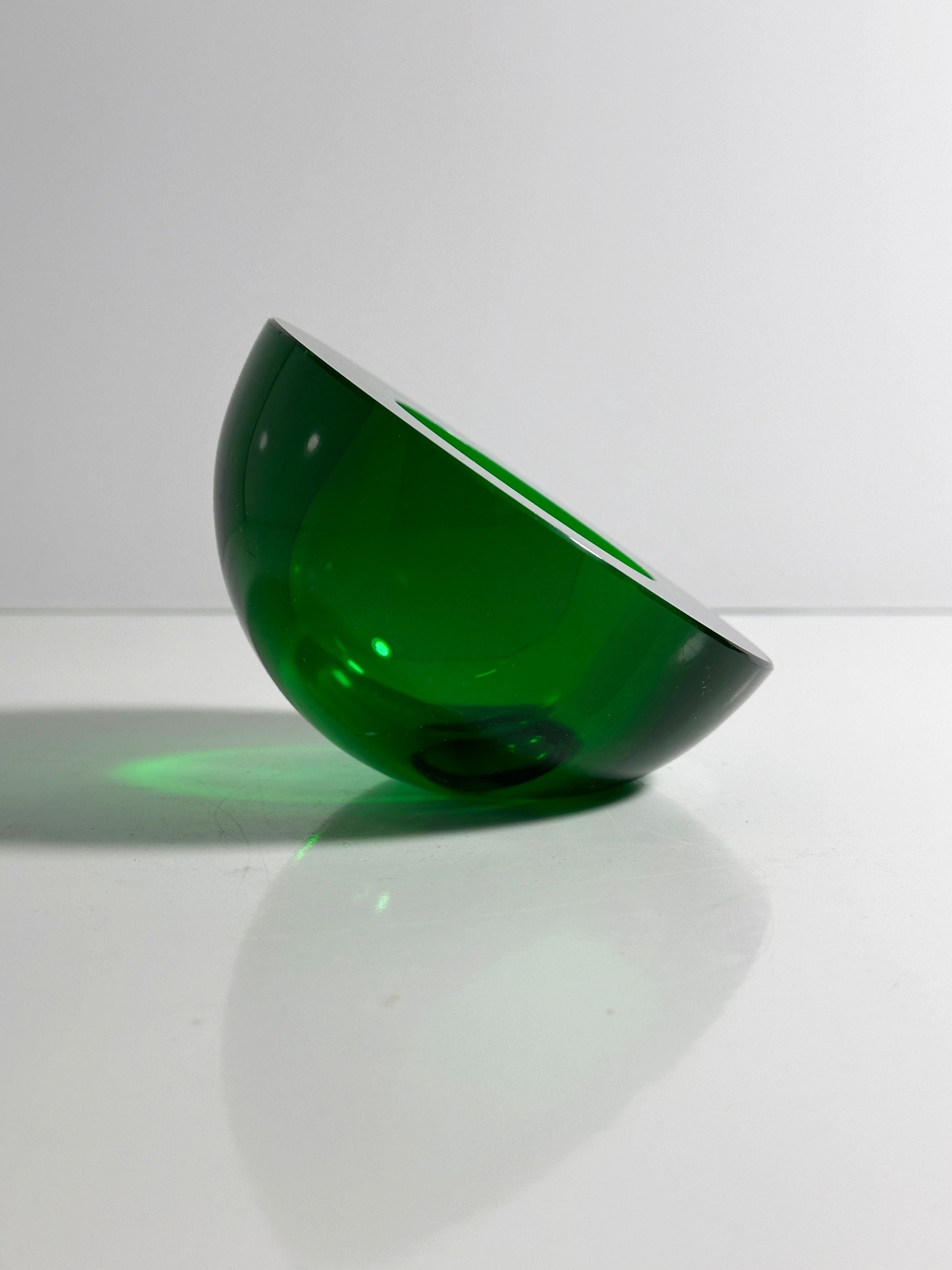 A semi-transparent, green 1960s Space Age Glass Ashtray by Dodo Vintage rests on its side on a white surface against a plain background, casting soft shadows and slight green reflections.