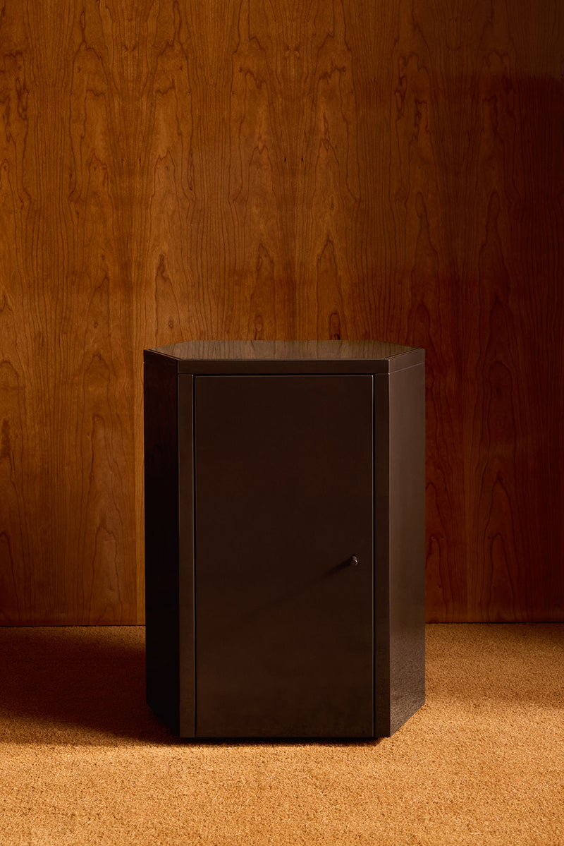 Dark lacquer Park nightstand against wood paneled wall