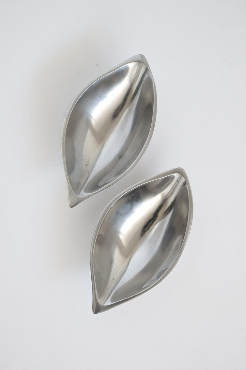 Two polished silver leaf-shaped serving dishes on white background