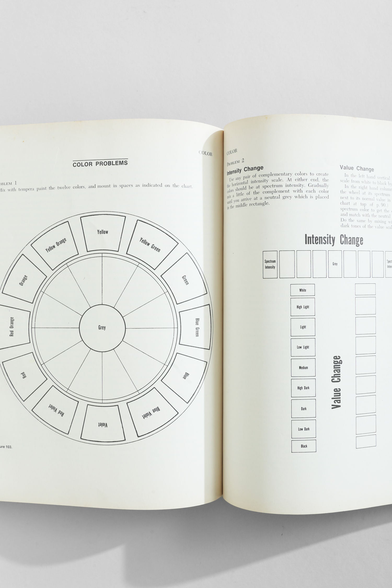 The Villa 'Art Fundamentals' Book opens to reveal a color wheel diagram with labeled hues on one page and black-and-white "Intensity Change" and "Value Change" charts on the other—ideal for studying art basics.