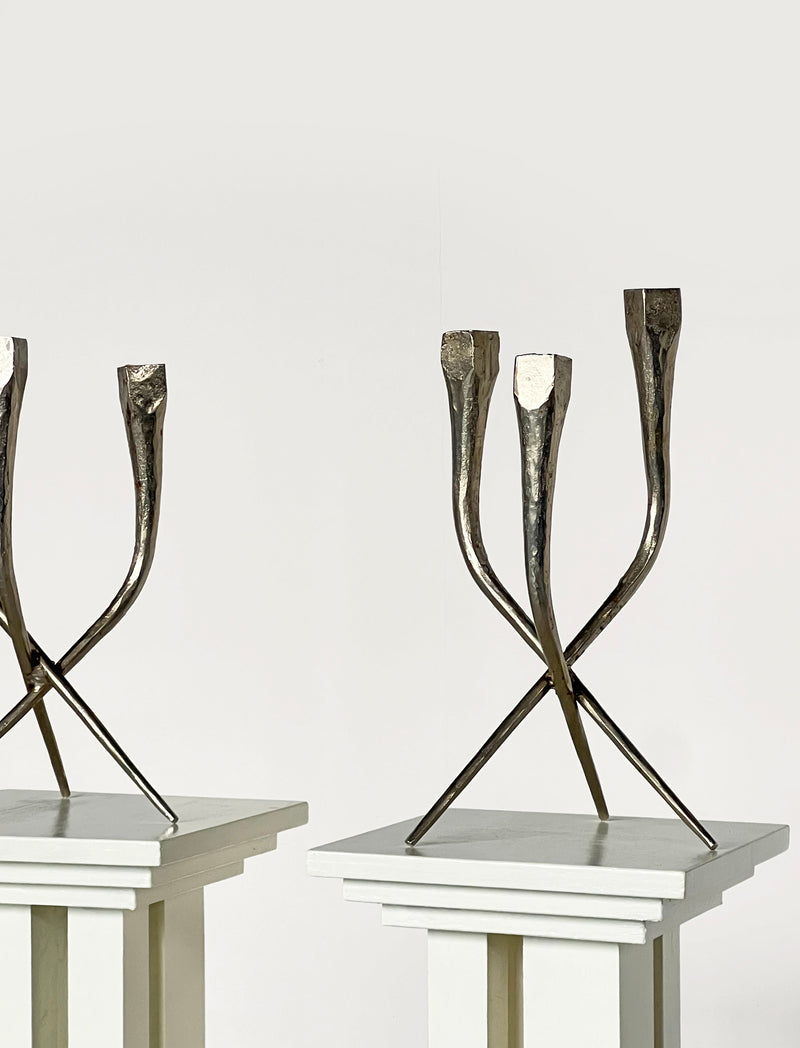Brutalist bronze candleholders with crossed angular legs on pedestals