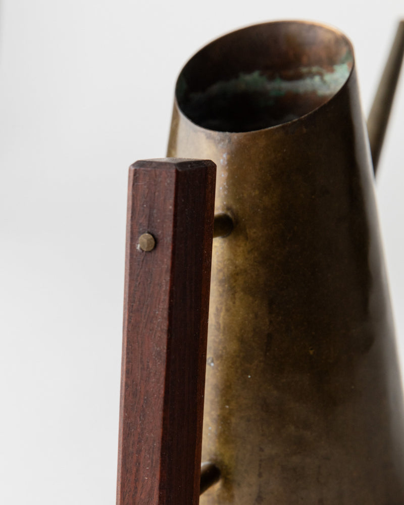 Brass watering can handle detail showing wood and metal construction