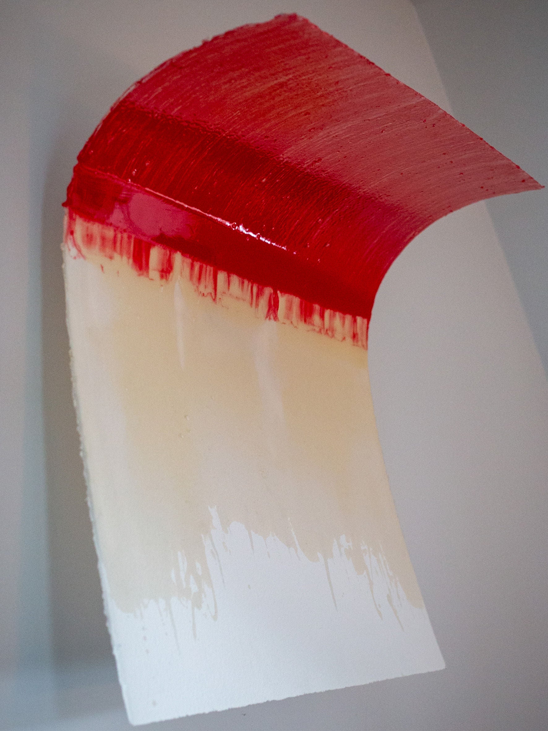 The "Red Curve" Epoxy Sculpture by STUDIOPOLS is a unique abstract piece with a curved, vertical surface that resembles cold-pressed watercolor paper. It showcases a captivating gradient starting with red at the top and fading to white at the bottom. Its smooth texture beautifully reflects light, highlighting the sculpture's vivid colors.