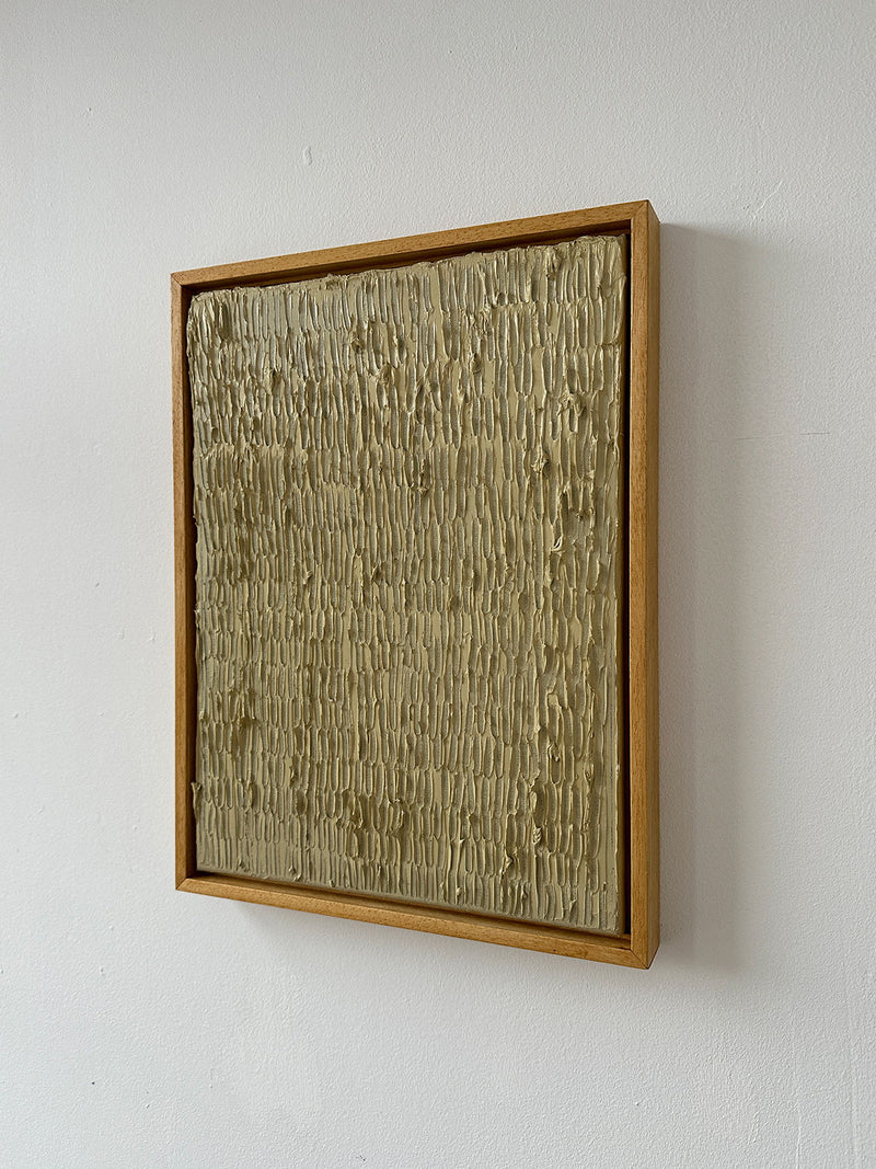 The "Buff Titanium" painting by Roi Elmaliah is a textured, square artwork showcasing vertical ridges on a beige surface. Crafted with oil on canvas, it is surrounded by a thin wooden border and mounted on a white wall.