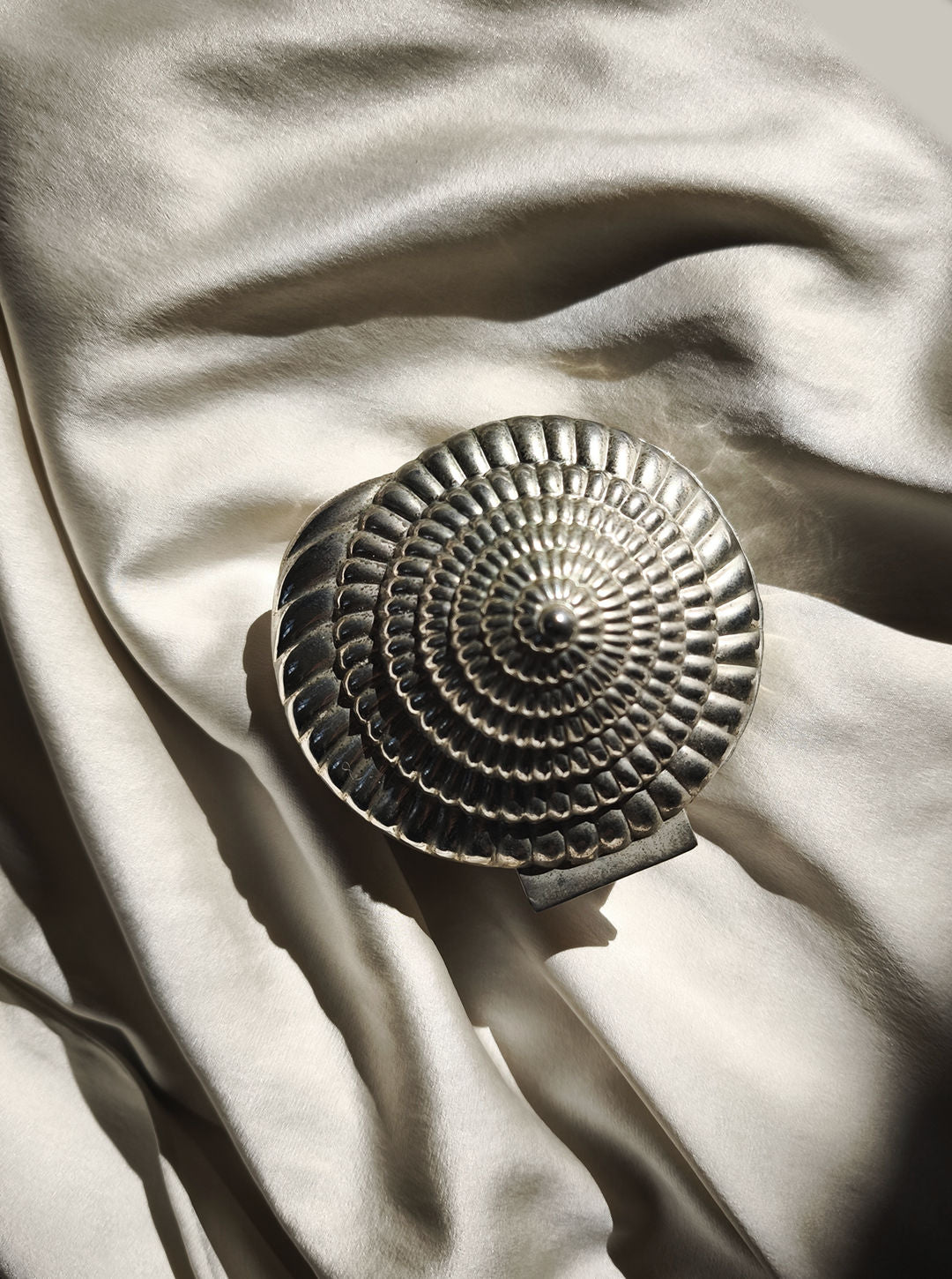 The Les Objoies Silver-plated Shell Box sits gracefully upon a backdrop of crumpled cream-colored silk fabric, casting delicate shadows under gentle lighting.