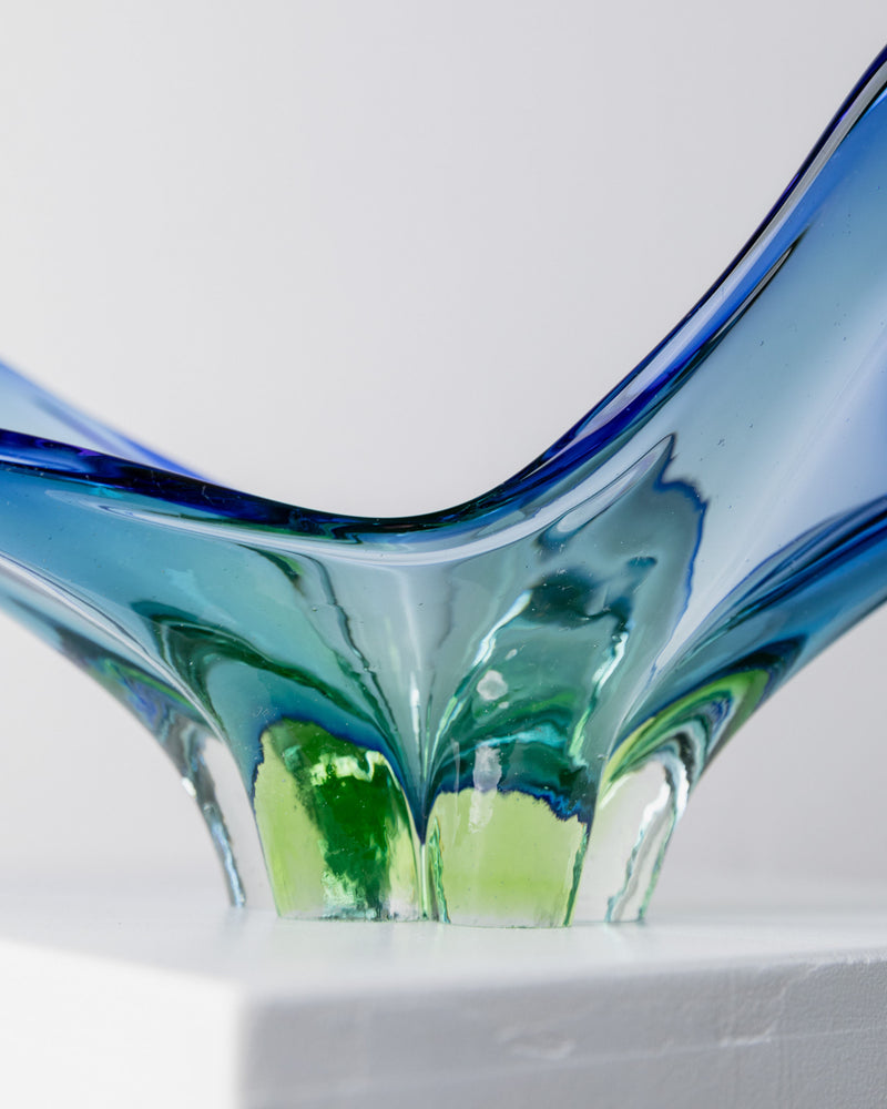 A close-up of the Murano Glass Sommerso Centerpiece 70s by Bottega Jacobs in blue and green, showcasing smooth, curved lines. It rests on a white surface, revealing its elegant Sommerso design with flowing transparency and reflective beauty—perfect for art lovers.